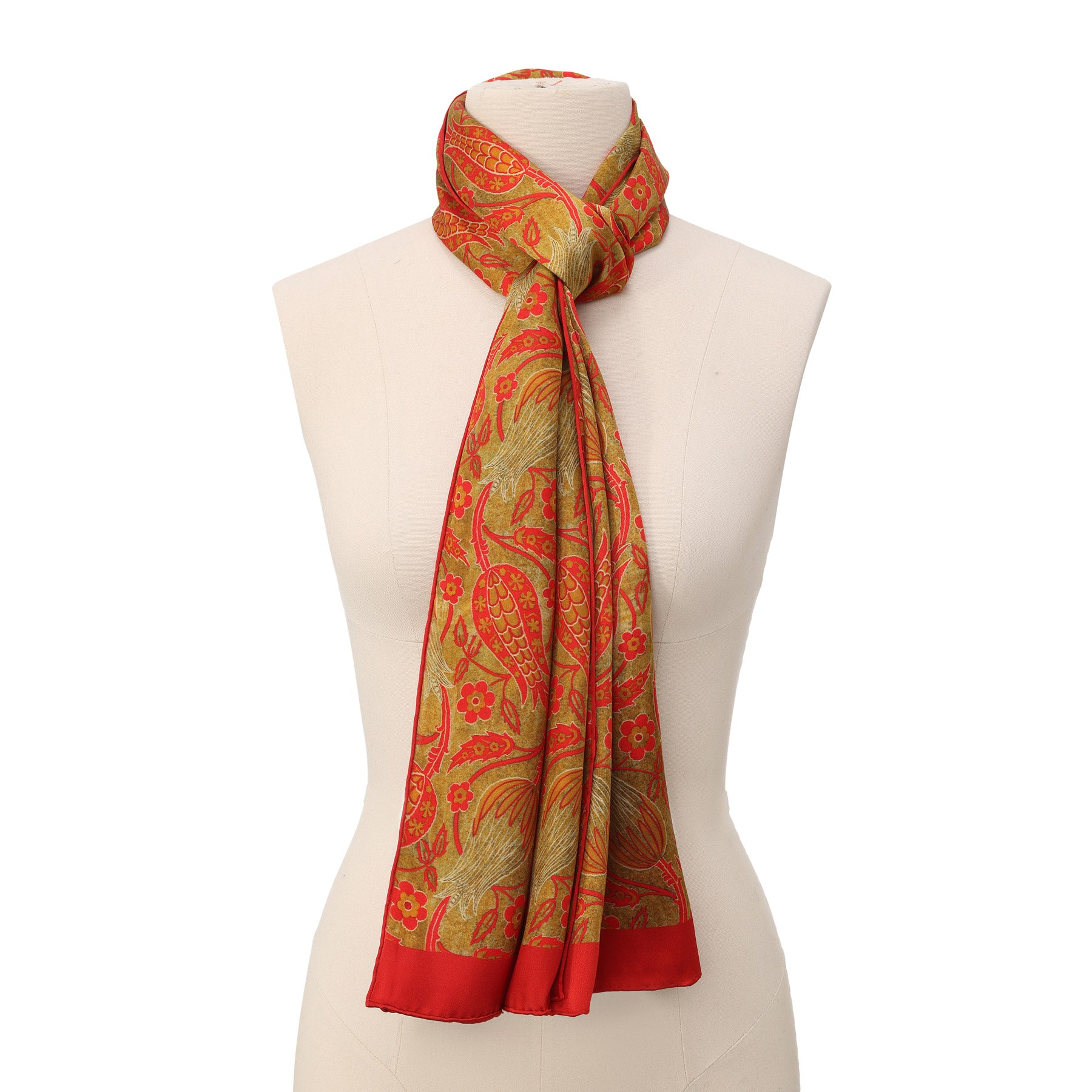 A close-up of the Floral Silk Scarf with Bold Red & Green Accents, showcasing intricate floral and bird patterns on a golden-yellow silk background with a soft, slightly glossy satin finish.