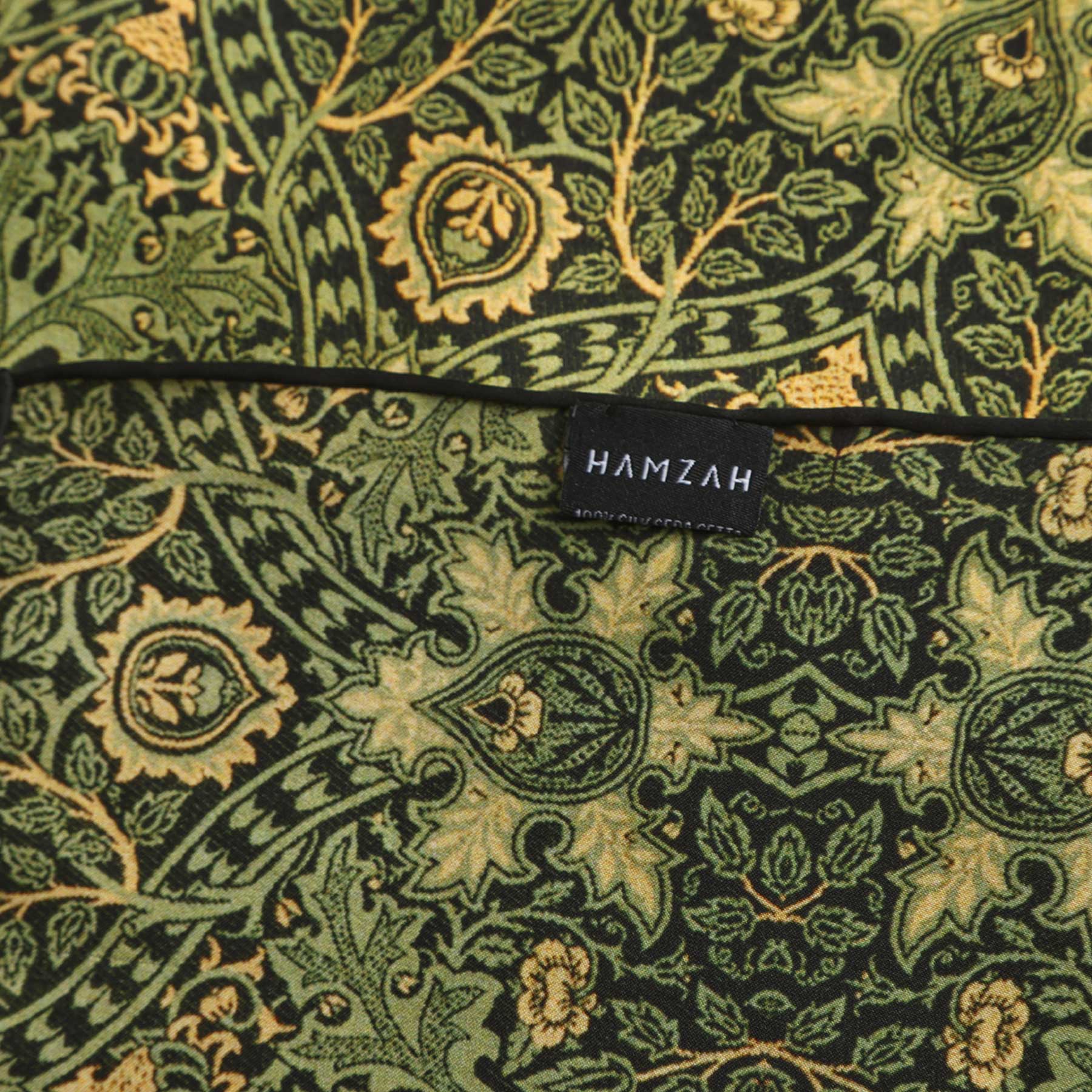 Close-up of the Vintage Green Silk Scarf with Ornate Gold Motifs, crafted from natural silk and detailed with intricate floral and geometric gold designs, softly draped on a white surface.