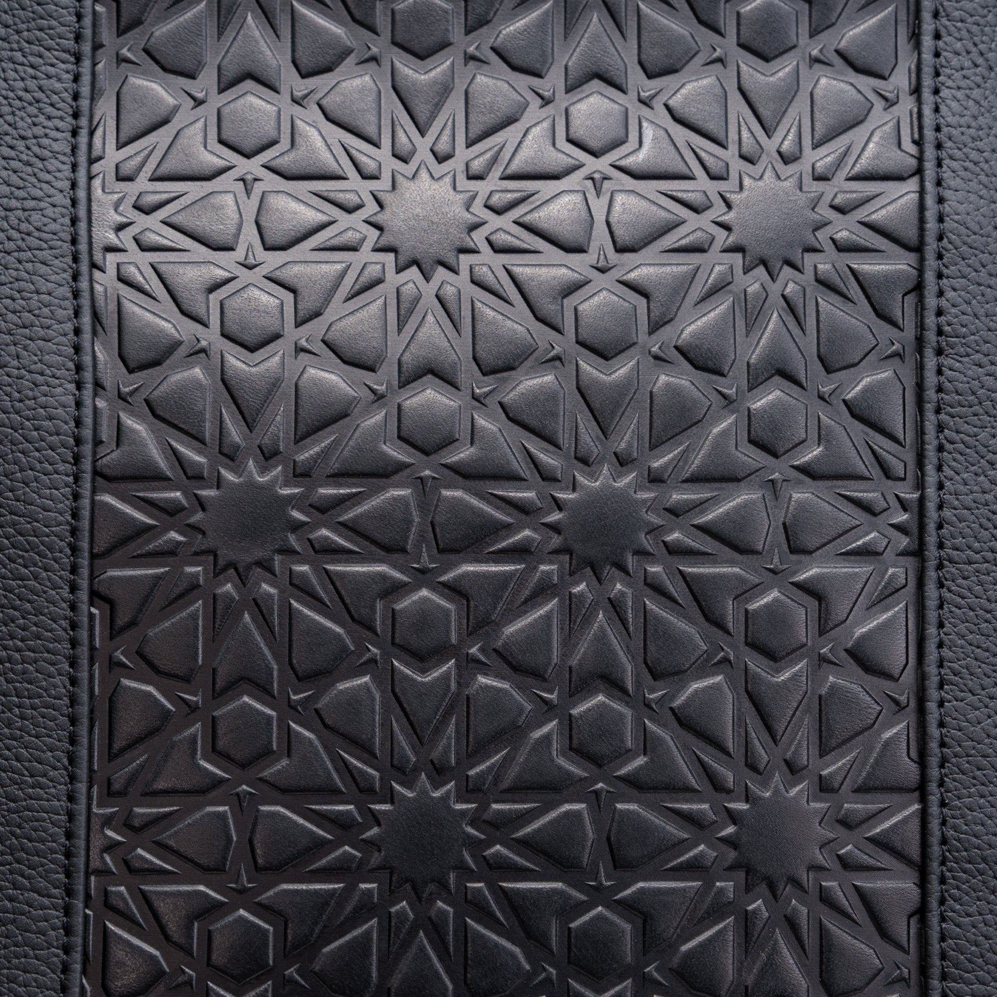 Close-up of the Black Leather Tote Bag - Alhambra Pattern Embossed, highlighting its intricate geometric star and interlocking line designs on luxurious Spanish leather.