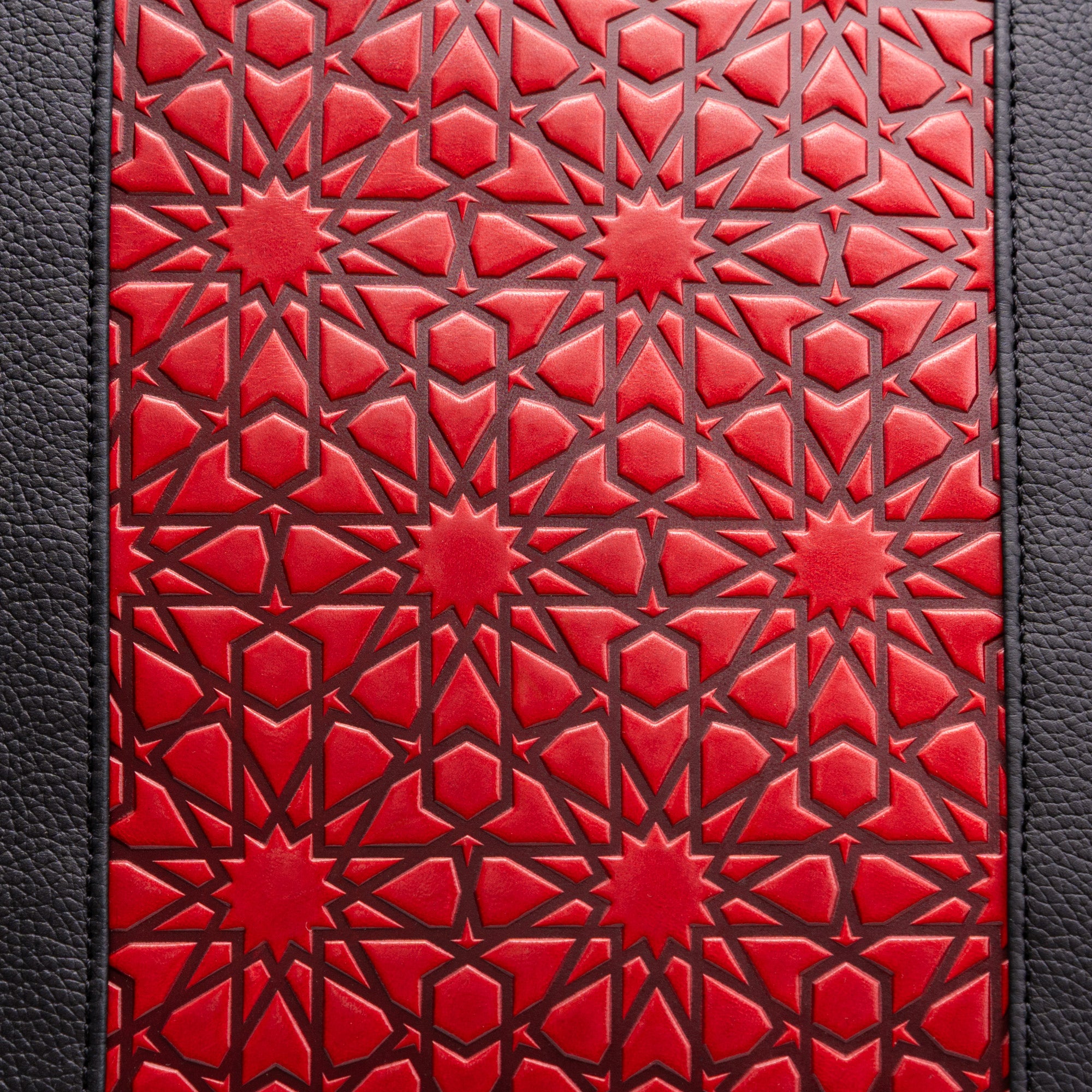 The Leather Tote Bag Red and Black with Islamic Art Embossed Pattern features striking red geometric star designs and interlocking lines, bordered by textured black sides, for a premium and elegant look.