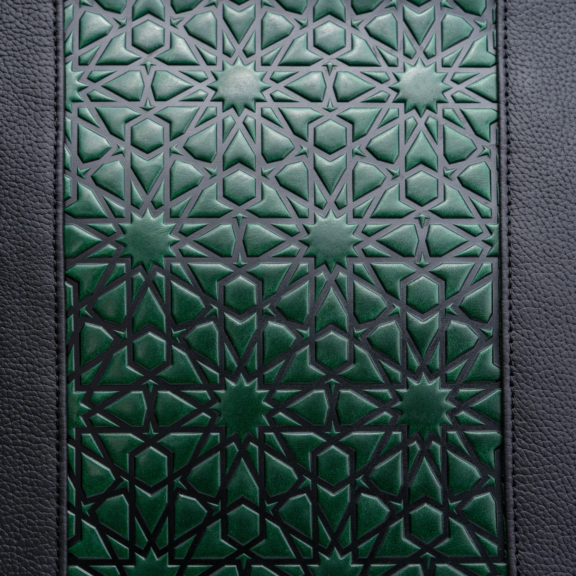 A close-up of the Leather Tote Bag Green and Black - Alhambra Pattern Embossed shows dark green and black interlocking stars and hexagons, bordered by textured black Spanish leather on both sides.