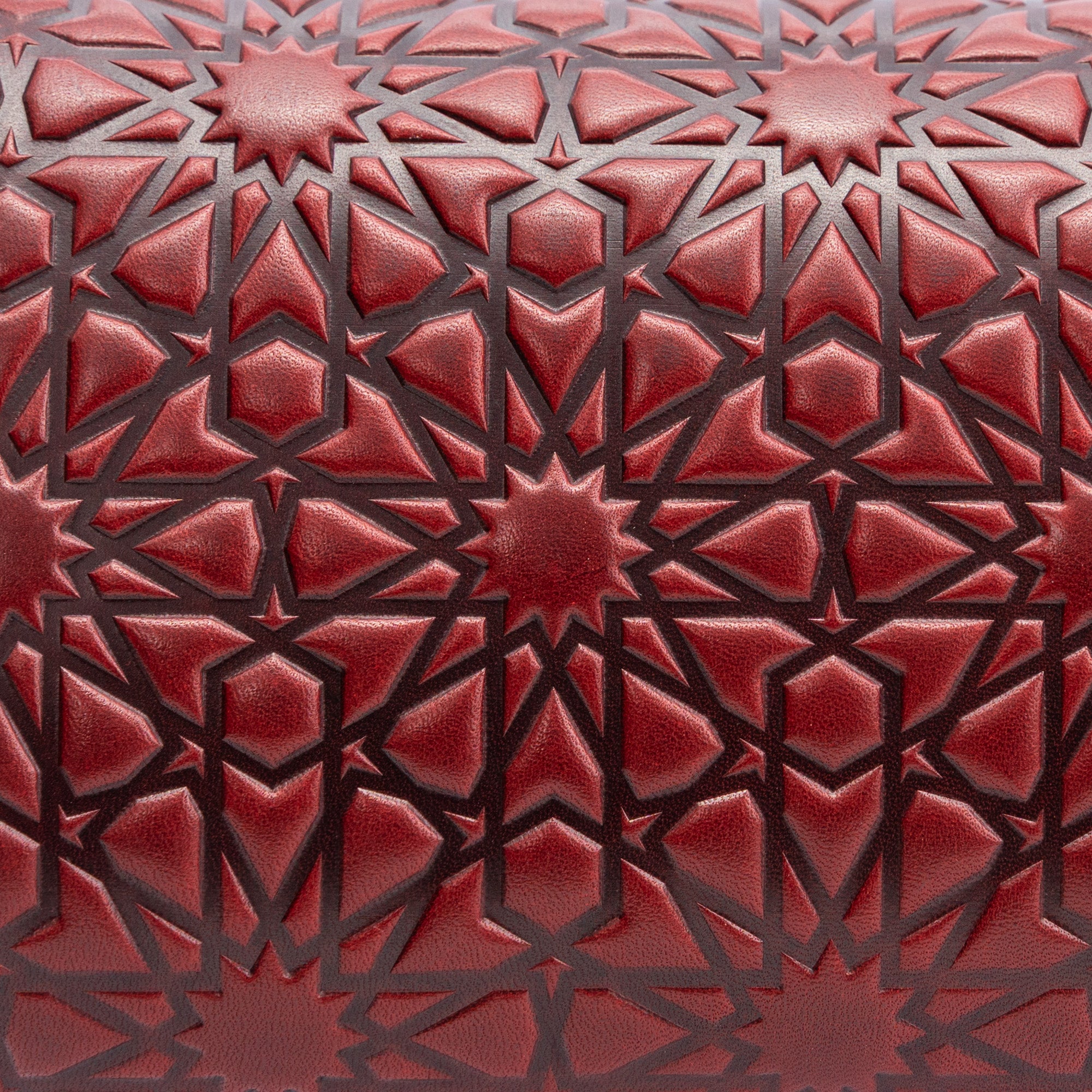 A close-up of the Small Burgundy Leather Bag Bayarcal, handmade from vegetable-tanned leather and embossed with a geometric star pattern inspired by Islamic art, featuring interlocking shapes and darkened lines for contrast.