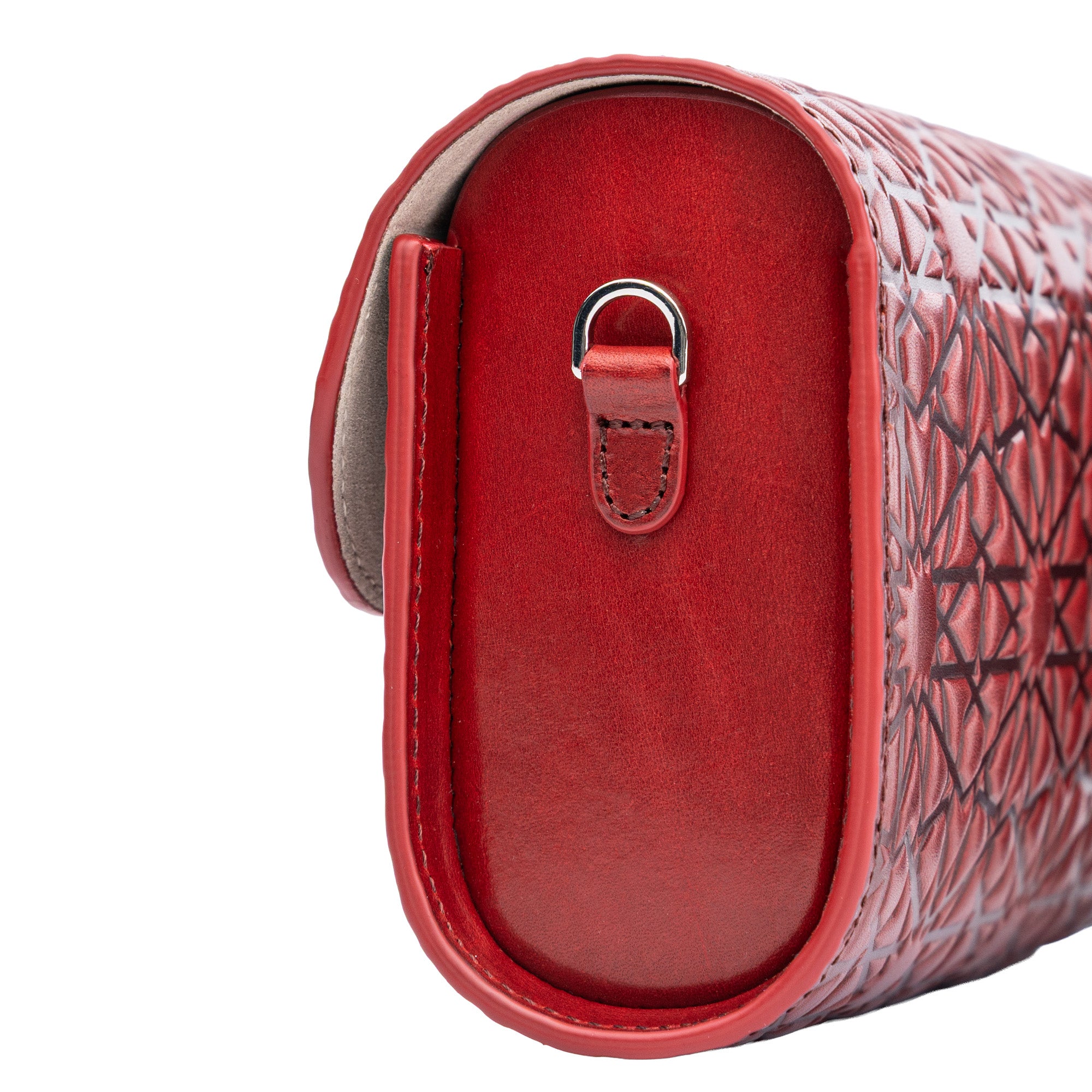 Close-up of the Small Burgundy Leather Bag Bayarcal, handmade from vegetable-tanned leather, showcasing a textured geometric pattern, visible stitching, side metal ring, rounded edges, and subtle Islamic-inspired embossing.