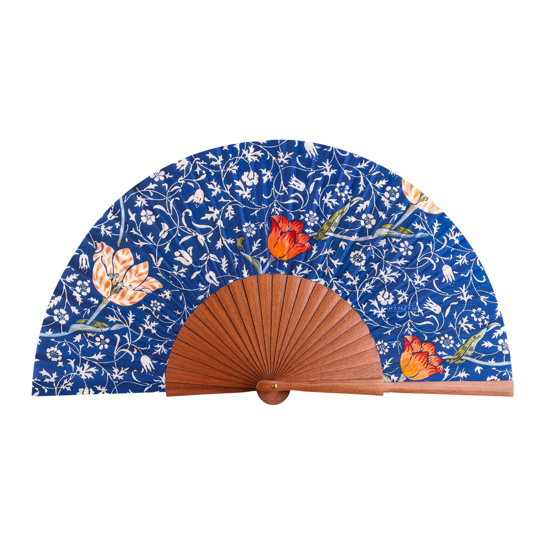 The Natural Silk Fan W. Morris Print Gálata features a blue backdrop with white floral designs and orange-red flowers on natural silk, highlighting refined Spanish craftsmanship and elegant wooden ribs.