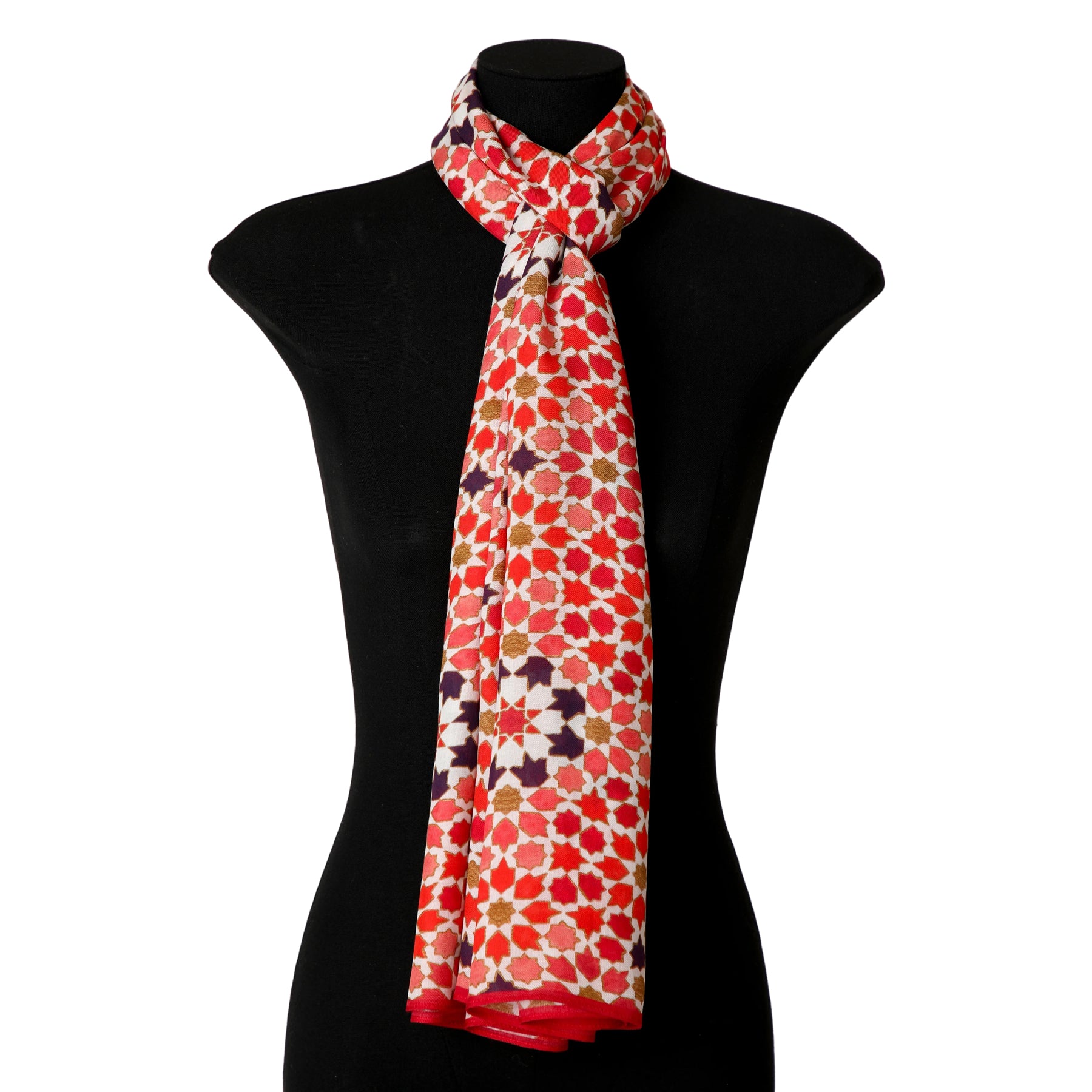 A mannequin showcases the Modal Hijab with Islamic Design Red - Alhambra, featuring a soft, long headscarf with a red, white, orange, and black geometric mosaic pattern draped loosely around the neck.