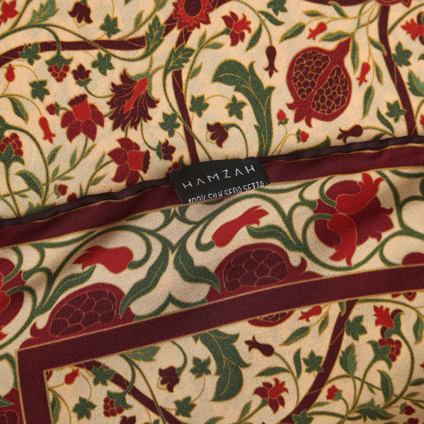 Rectangular black packaging with HAMZAH at the top. A vertical art nouveau floral and pomegranate panel in red, green