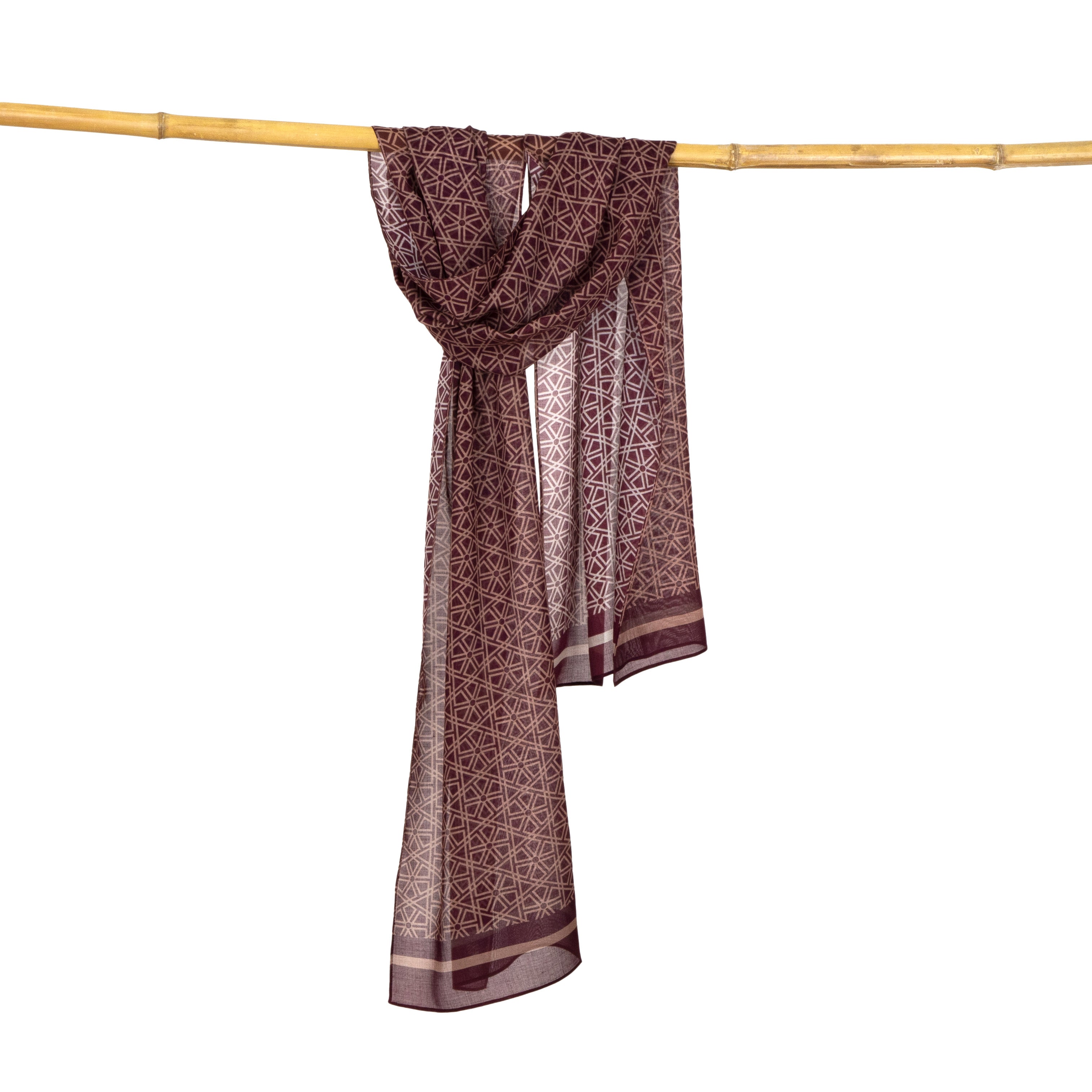 The Red and Beige Scarf Taif v2, featuring Alhambra-inspired motifs, is draped over a horizontal bamboo pole against a white background.