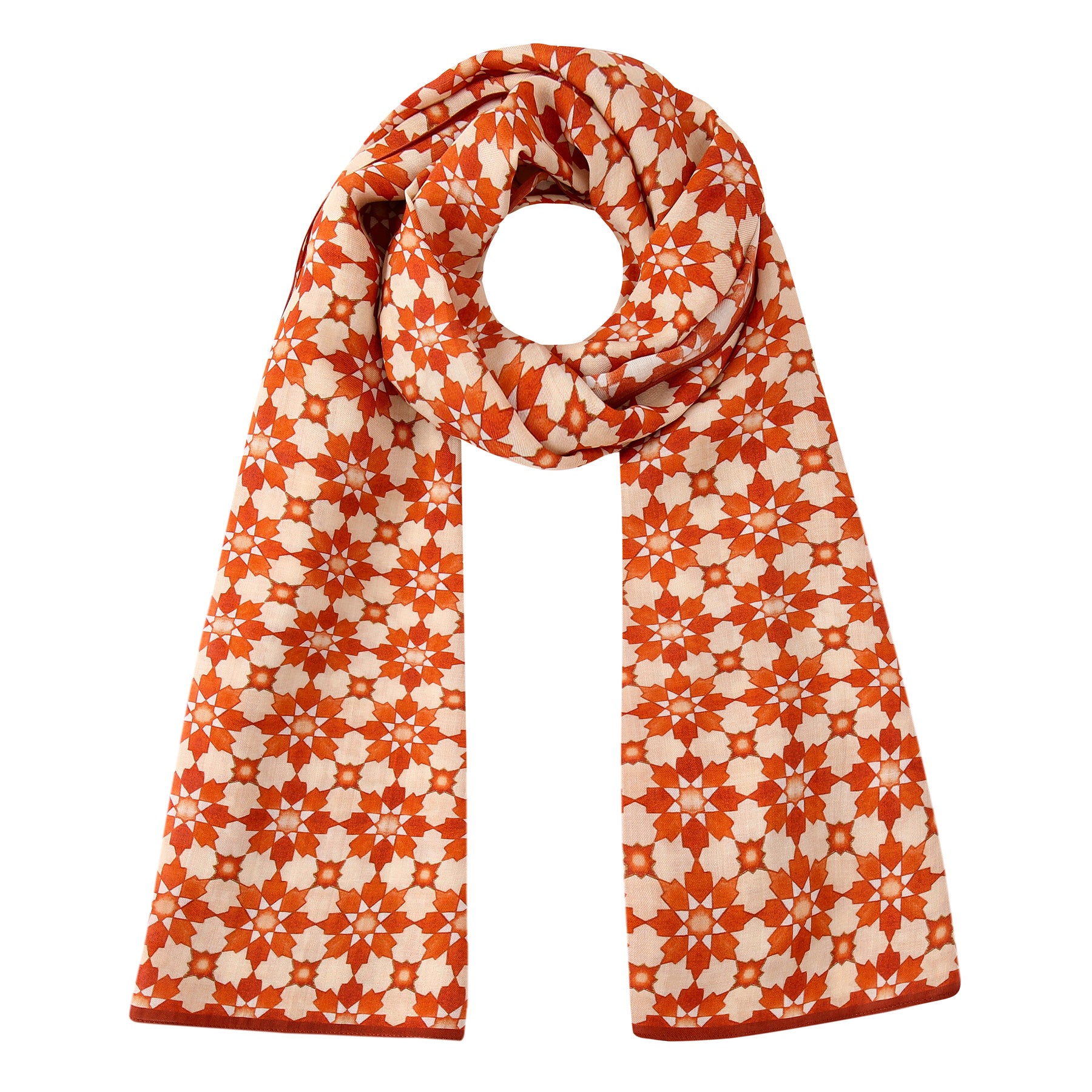 The Orange Scarf with Islamic Pattern Print is inspired by the Alhambra, featuring a repeating pattern of small white floral shapes and styled with one end looped and both ends hanging down.