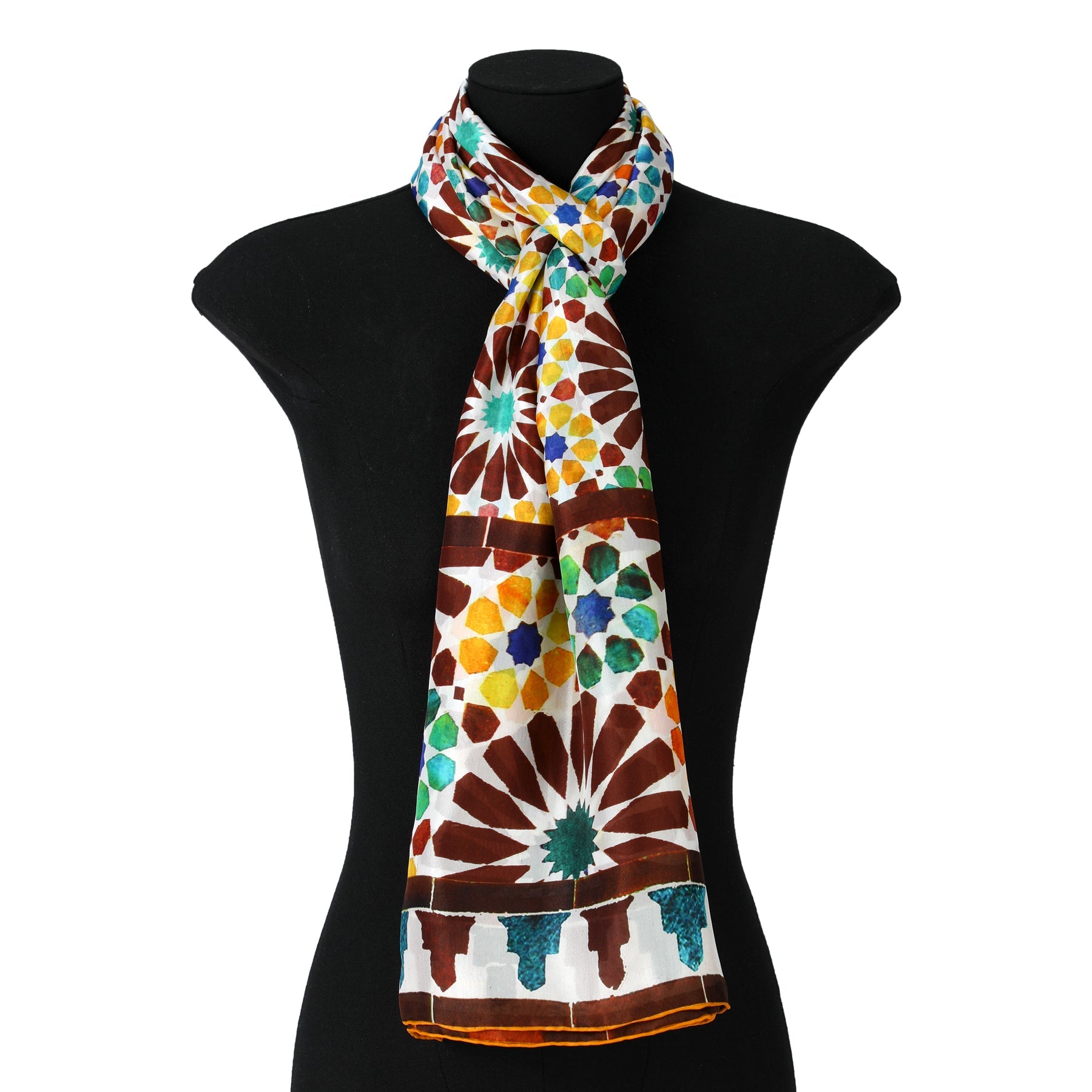 The Brown and Yellow Silk Scarf Garnata features vibrant geometric and floral designs inspired by Islamic Art in shades of brown, blue, green, yellow, and turquoise on a white background, elegantly draped on a black mannequin bust.