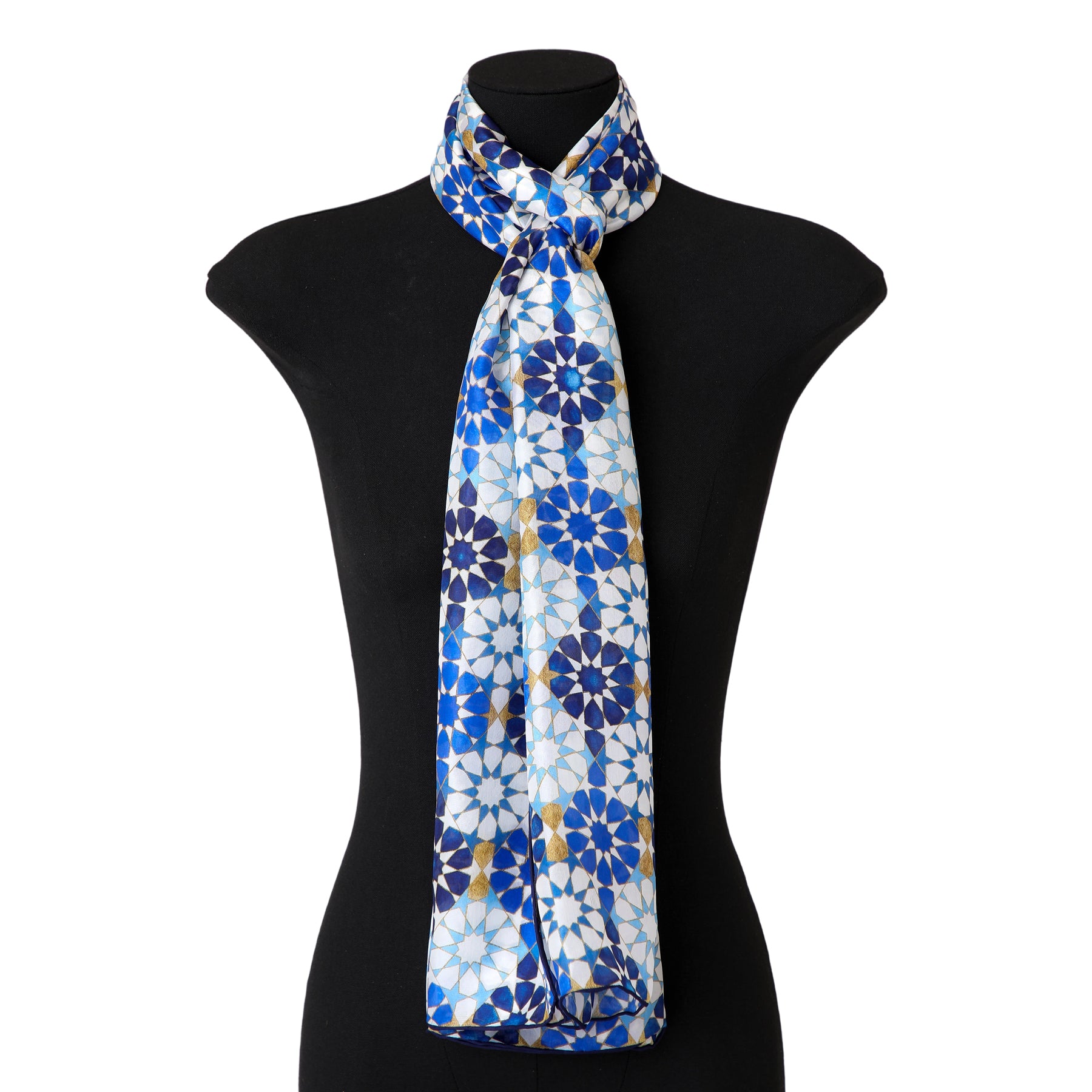 A black mannequin displays the Blue Silk Scarf with Islamic Pattern DalAhorra, featuring Andalusian geometric designs in blue, white, and gold silk, neatly tied around the neck.