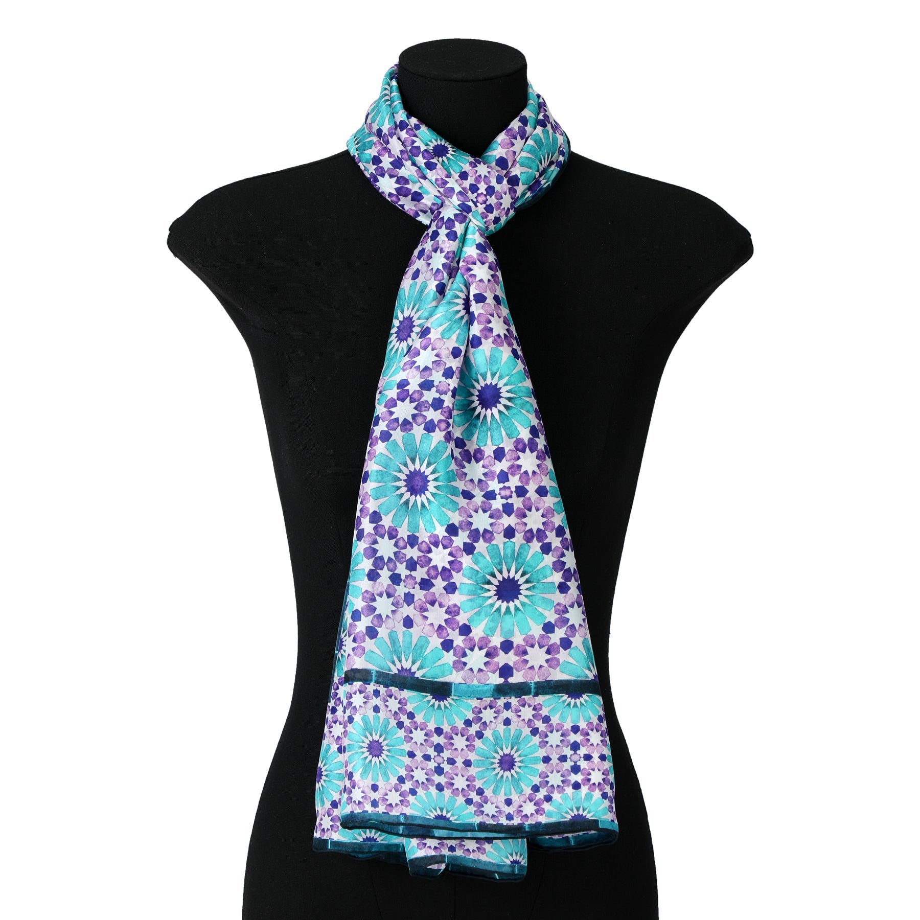 A mannequin showcases the Purple and Turquoise Silk Scarf Layla, featuring a vibrant geometric design inspired by Islamic architecture, draped gracefully around the neck and flowing down the front.