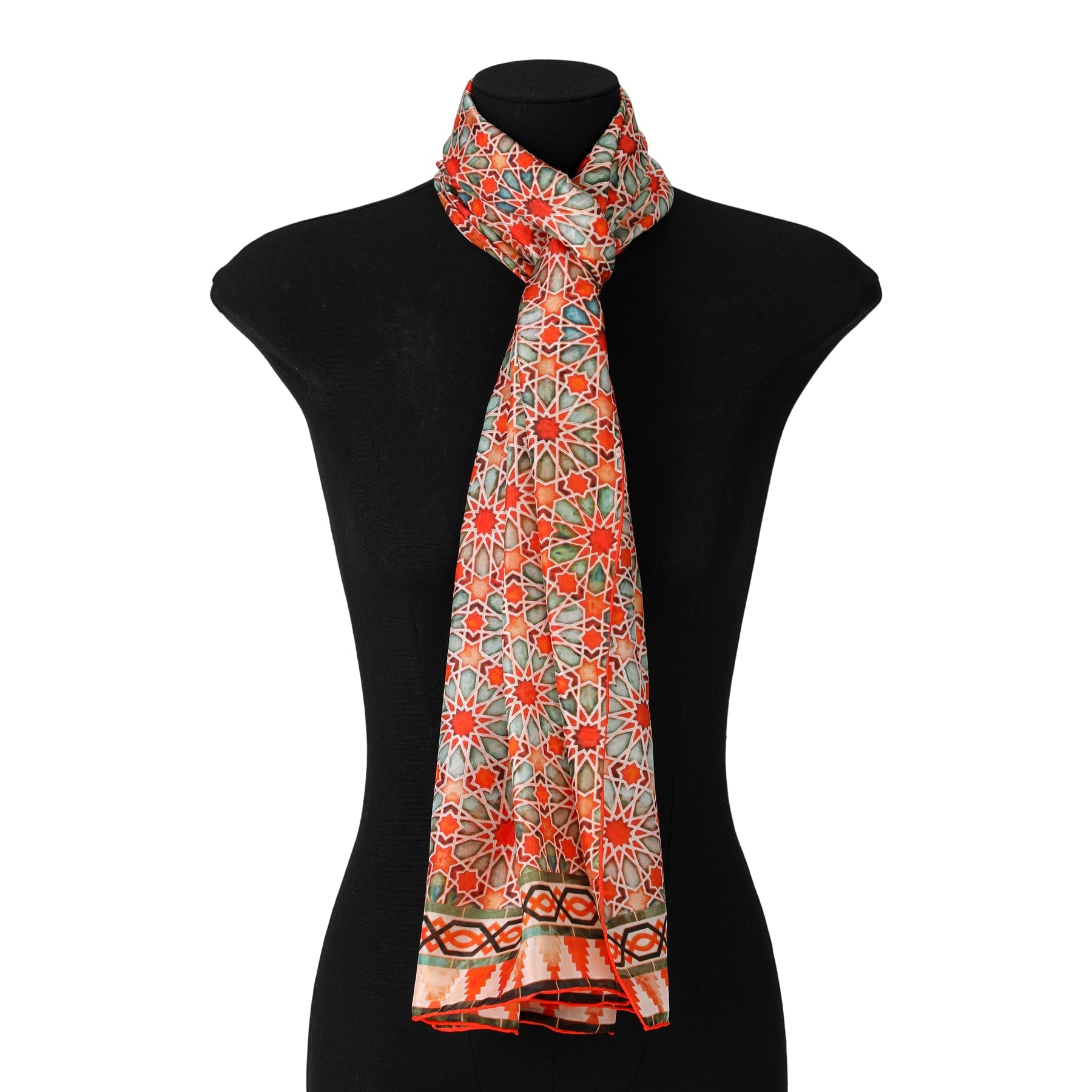 A mannequin displays the Orange Silk Scarf with Geometric Print Zellige, featuring a lightweight silk fabric and a vibrant mosaic-inspired pattern in orange, green, and beige tones, tied loosely around the neck.