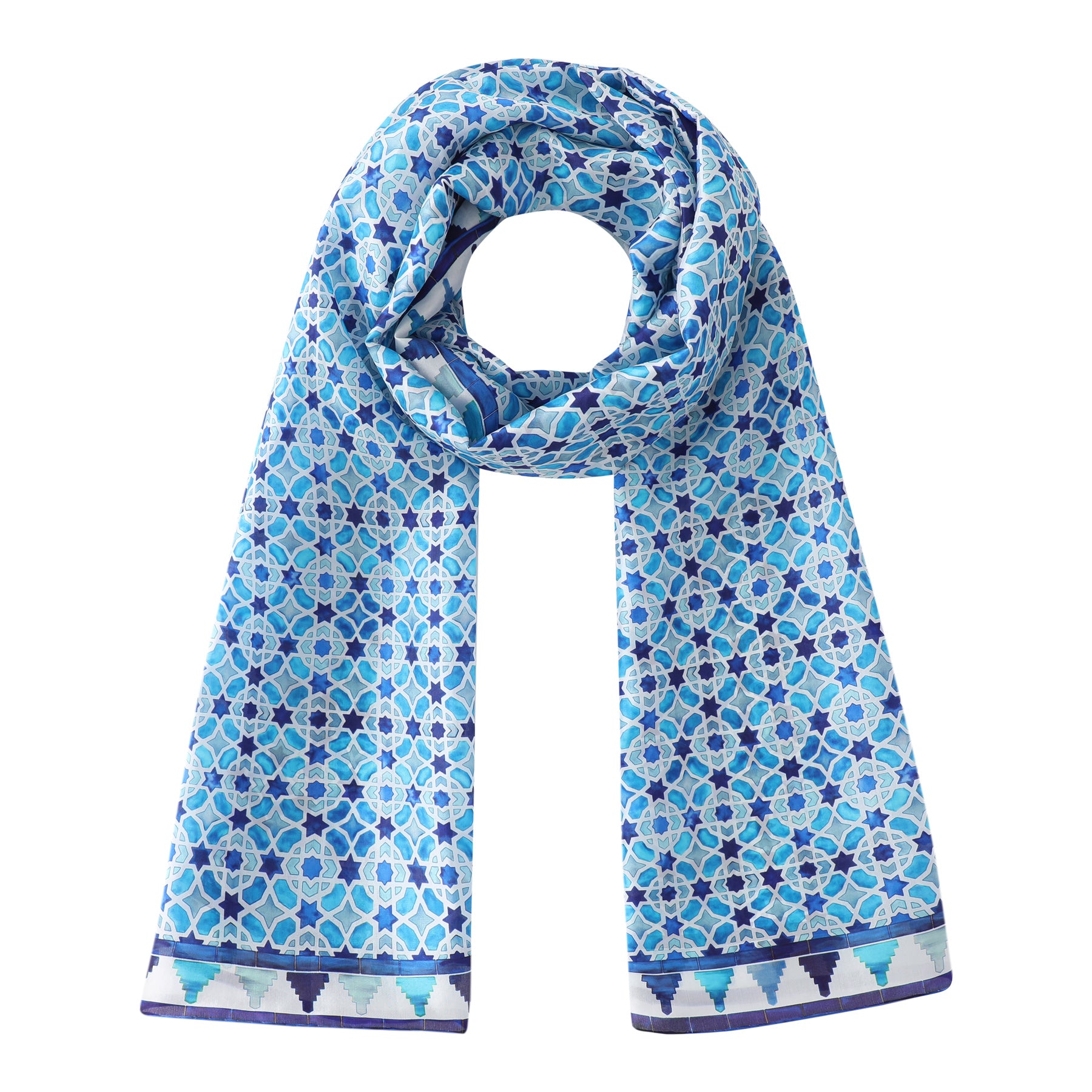 The Light Blue Silk Scarf Alcázar features blue and white silk with geometric and floral motifs inspired by Islamic art, displayed in a loop with hanging ends. A dark blue border with triangular detailing completes the design.