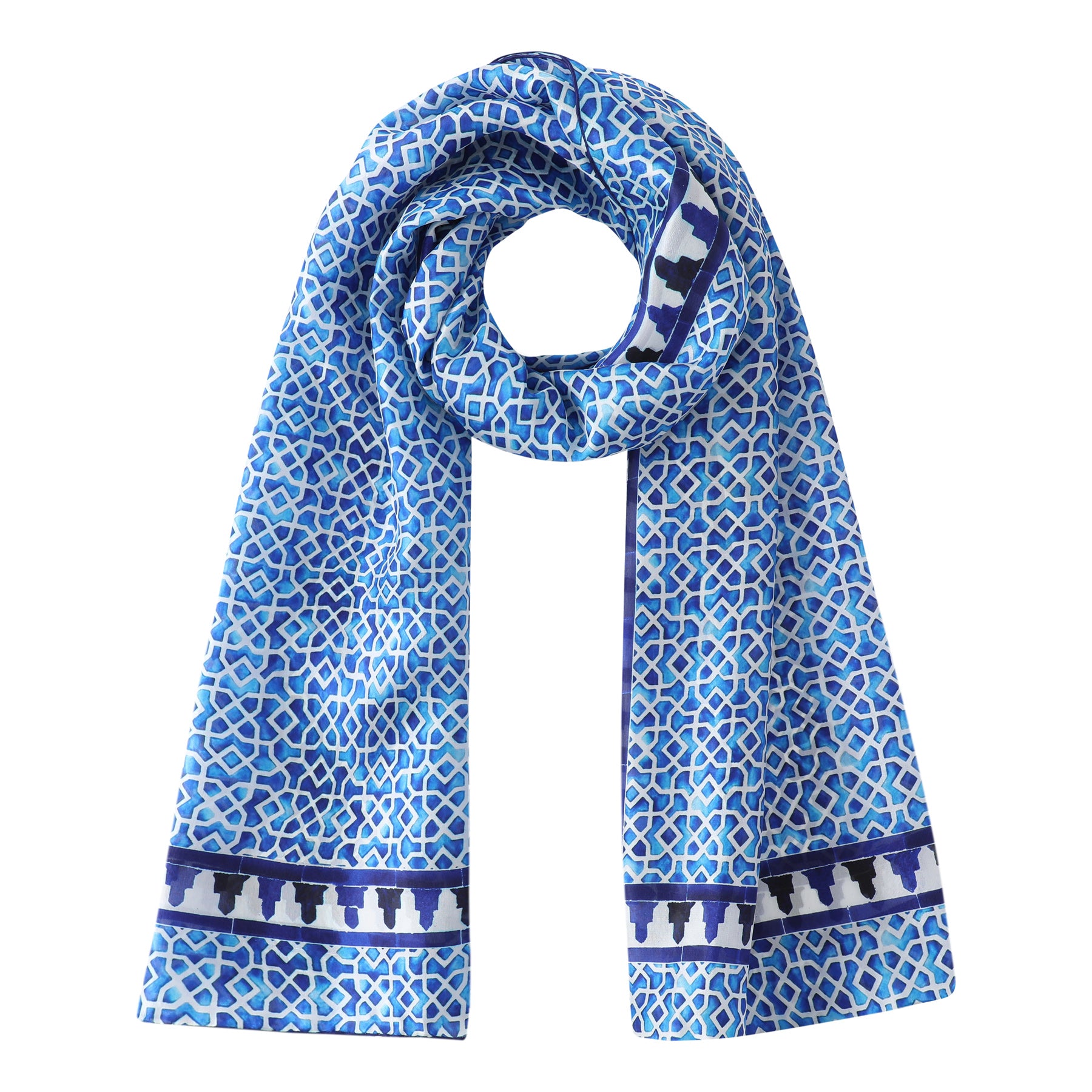 The Oblong Blue Silk Scarf Alcazaba showcases geometric patterns inspired by Islamic art in blue and white, accented with a decorative dark blue border at each end. Displayed on a white background.
