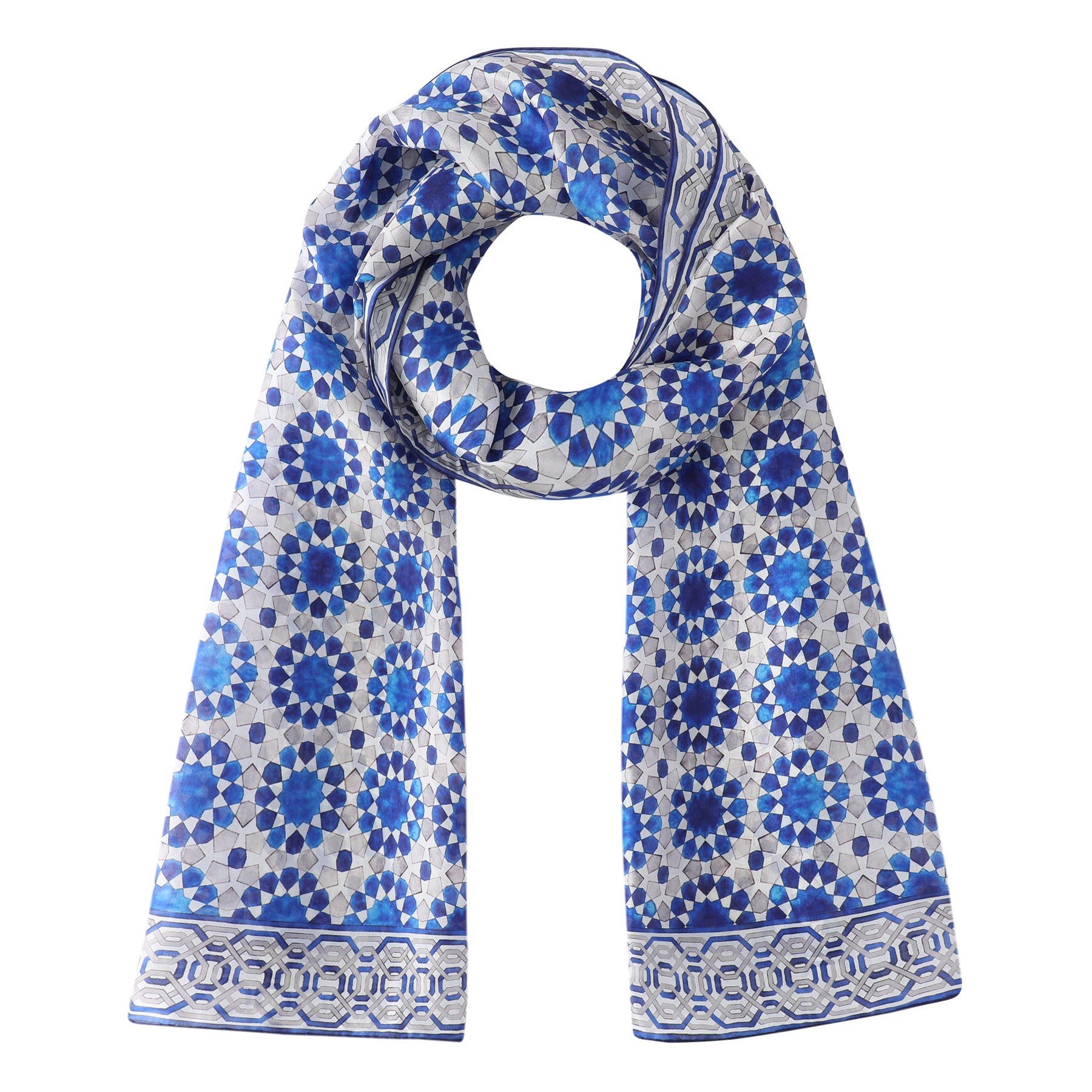 The Blue and Grey Silk Scarf Najma showcases a geometric mosaic pattern inspired by Islamic art, with interlocking circular and hexagonal shapes in blue, grey, and white, adding an elegant touch to any look.
