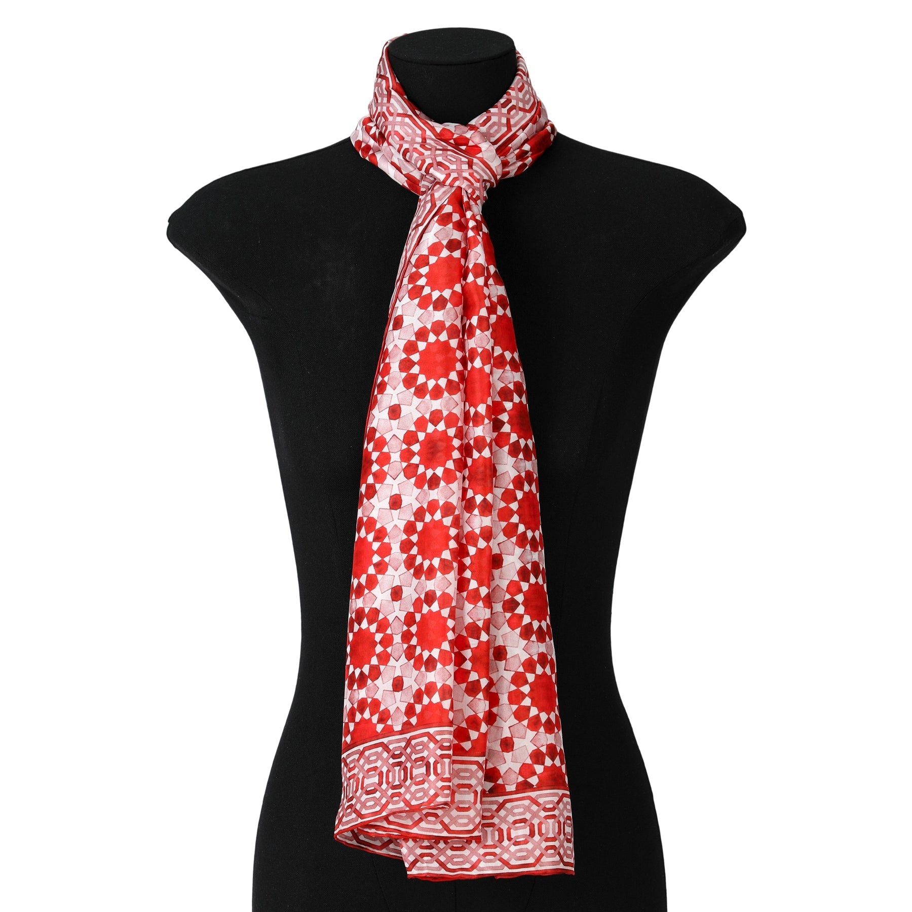 The Moroccan Inspired Red Silk Scarf Najma, featuring red and white floral and geometric patterns, is draped elegantly around the neck of a black mannequin torso.