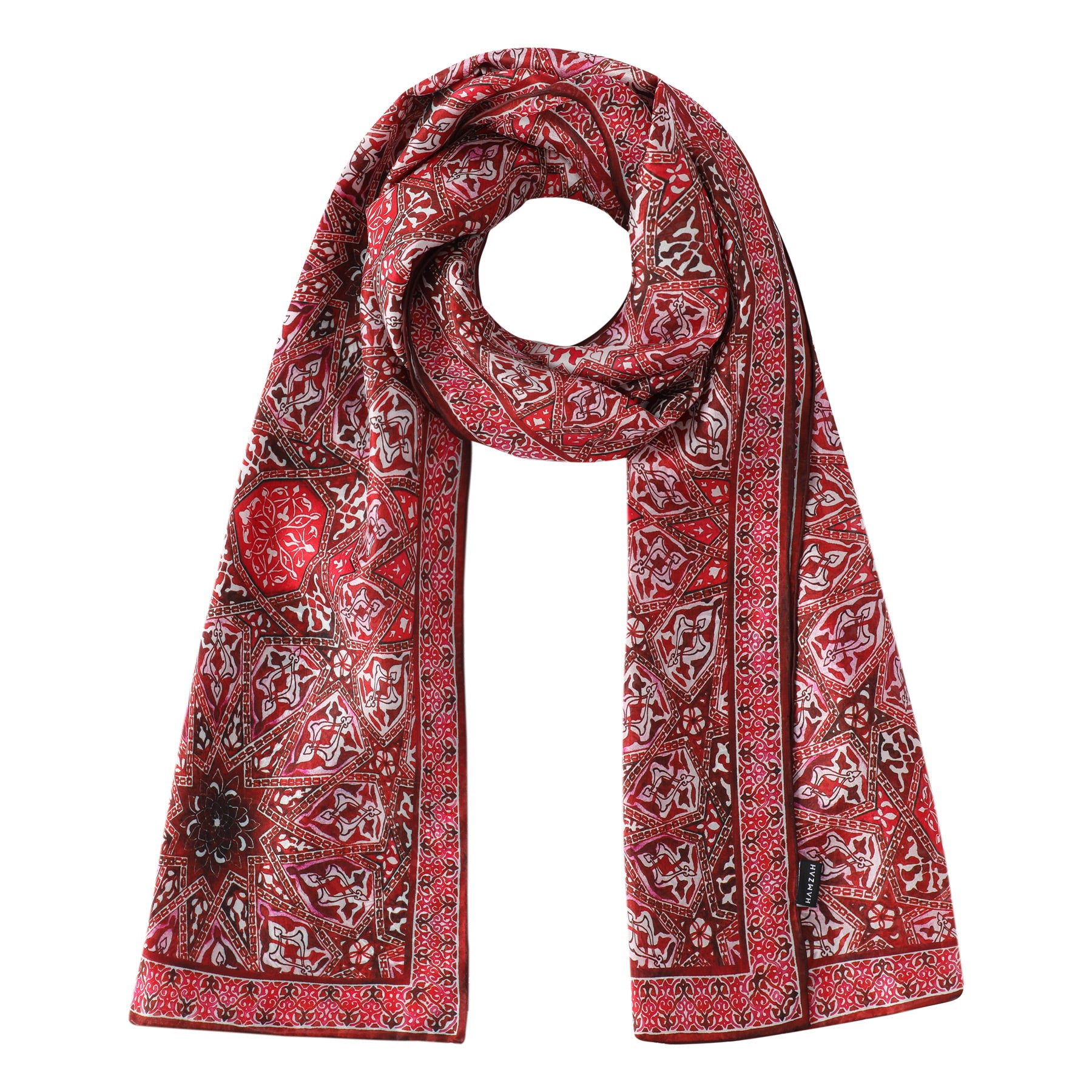 The Red Silk Scarf with Geometric Turkish Print features luxurious red silk adorned with intricate white and black geometric patterns and delicate floral designs, styled in a loop with both ends hanging down.