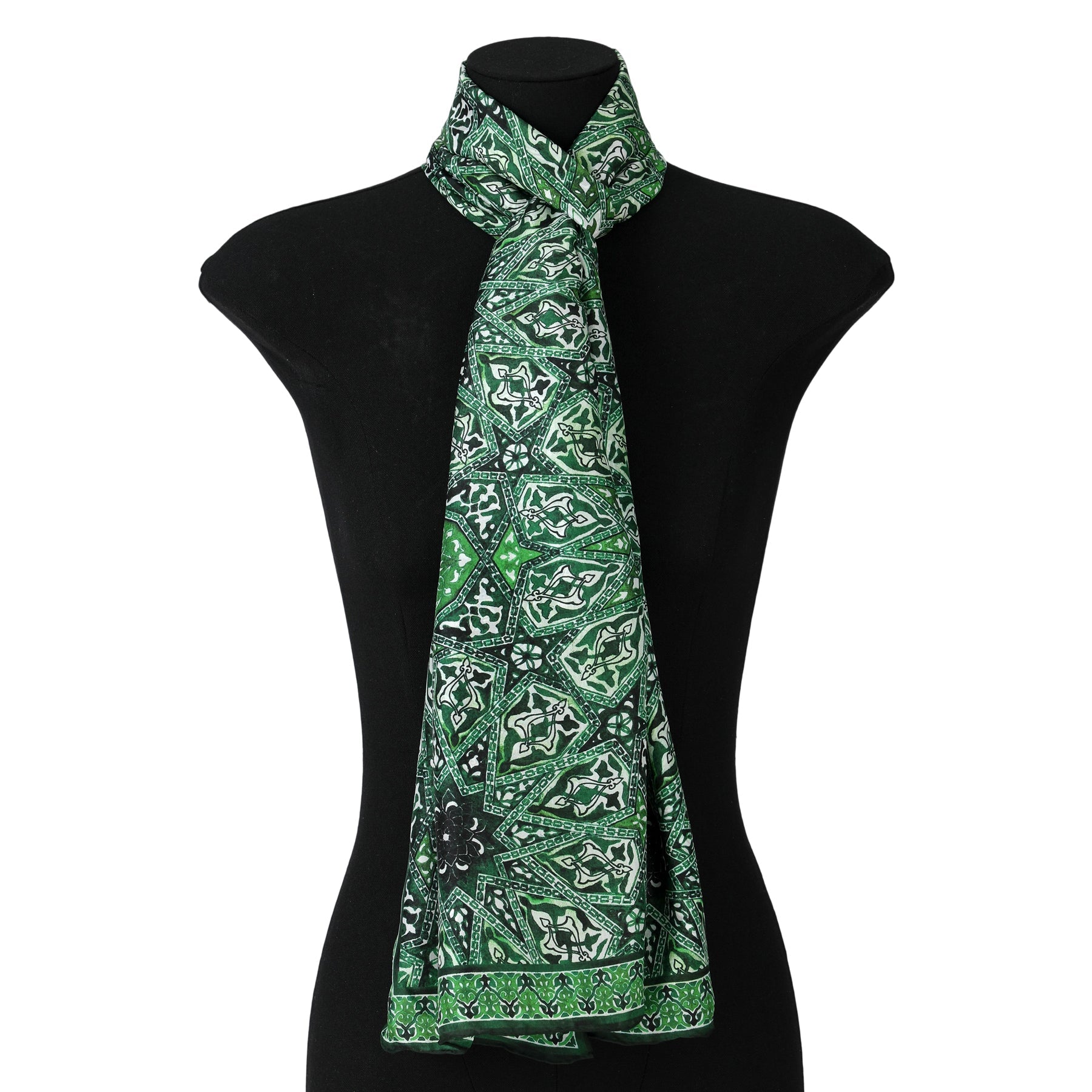 The Green Silk Neck Scarf Turkish Print, crafted from lightweight silk and featuring intricate white and black Turkish patterns, is draped loosely around a black dress form mannequin to highlight its detailed design.