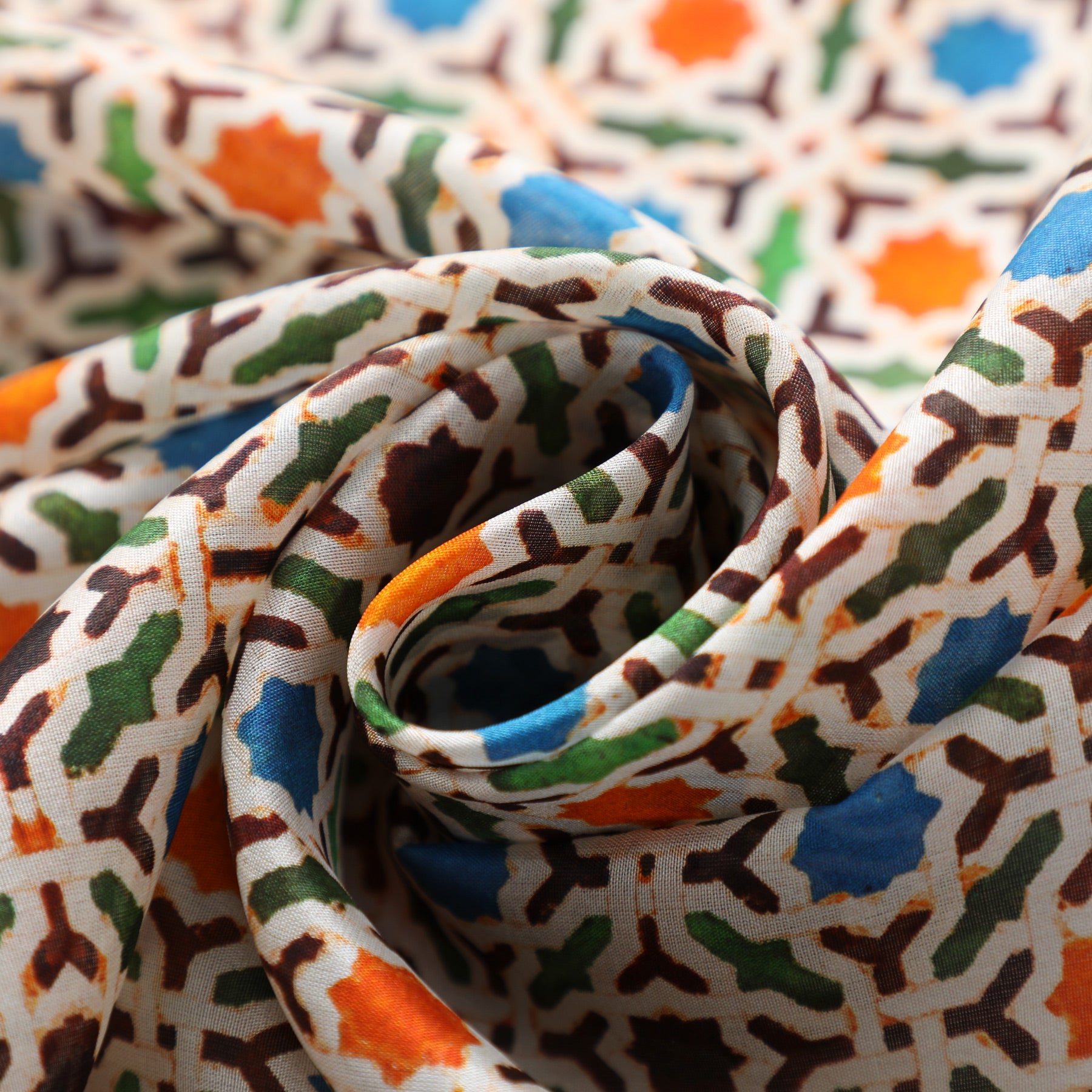 Close-up of the Colorful Silk Scarf with Geometric Print Nazarí, artistically twisted to showcase its rich silk texture and vibrant geometric pattern in blue, orange, and green inspired by Islamic art.