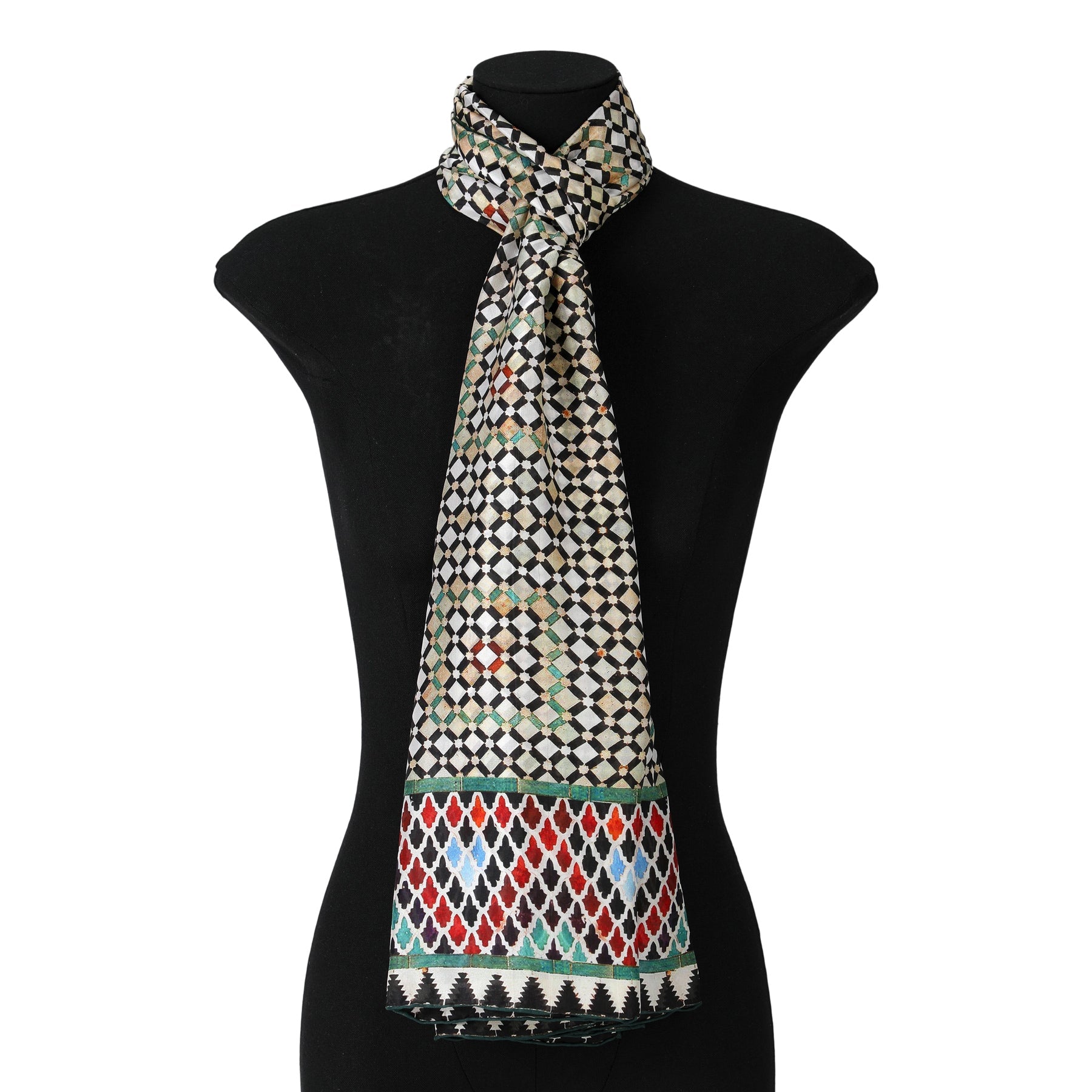 A black mannequin showcases the Colorful Large Silk Scarf Hub, featuring a geometric diamond pattern inspired by Moorish tiles in black, white, and green with red, blue, green accents and a decorative border at each end.