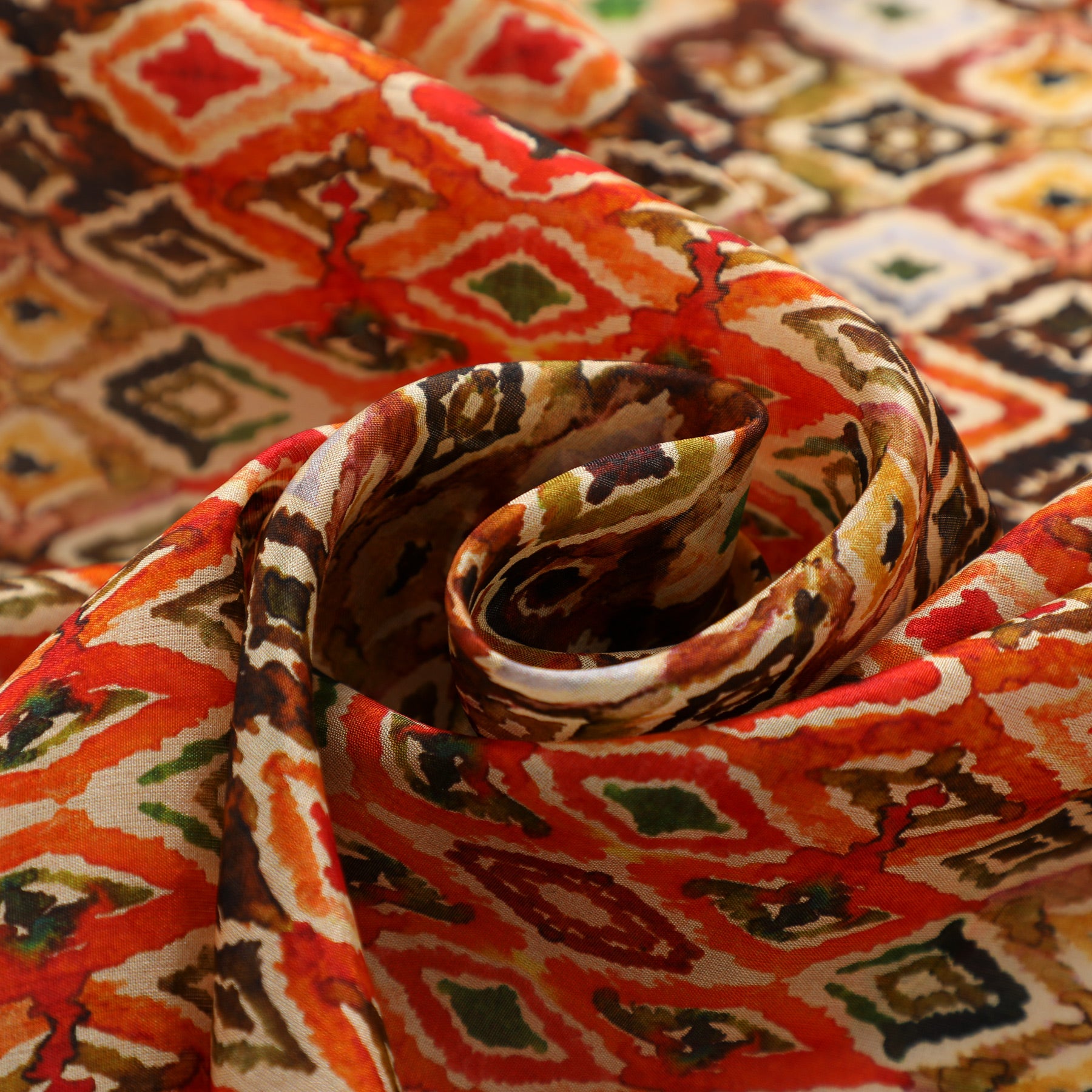 Close-up of the Multicolor Silk Scarf featuring an Ikat Ethnic Print in vibrant red, orange, brown, green, and white tones, artfully twisted into a spiral shape.