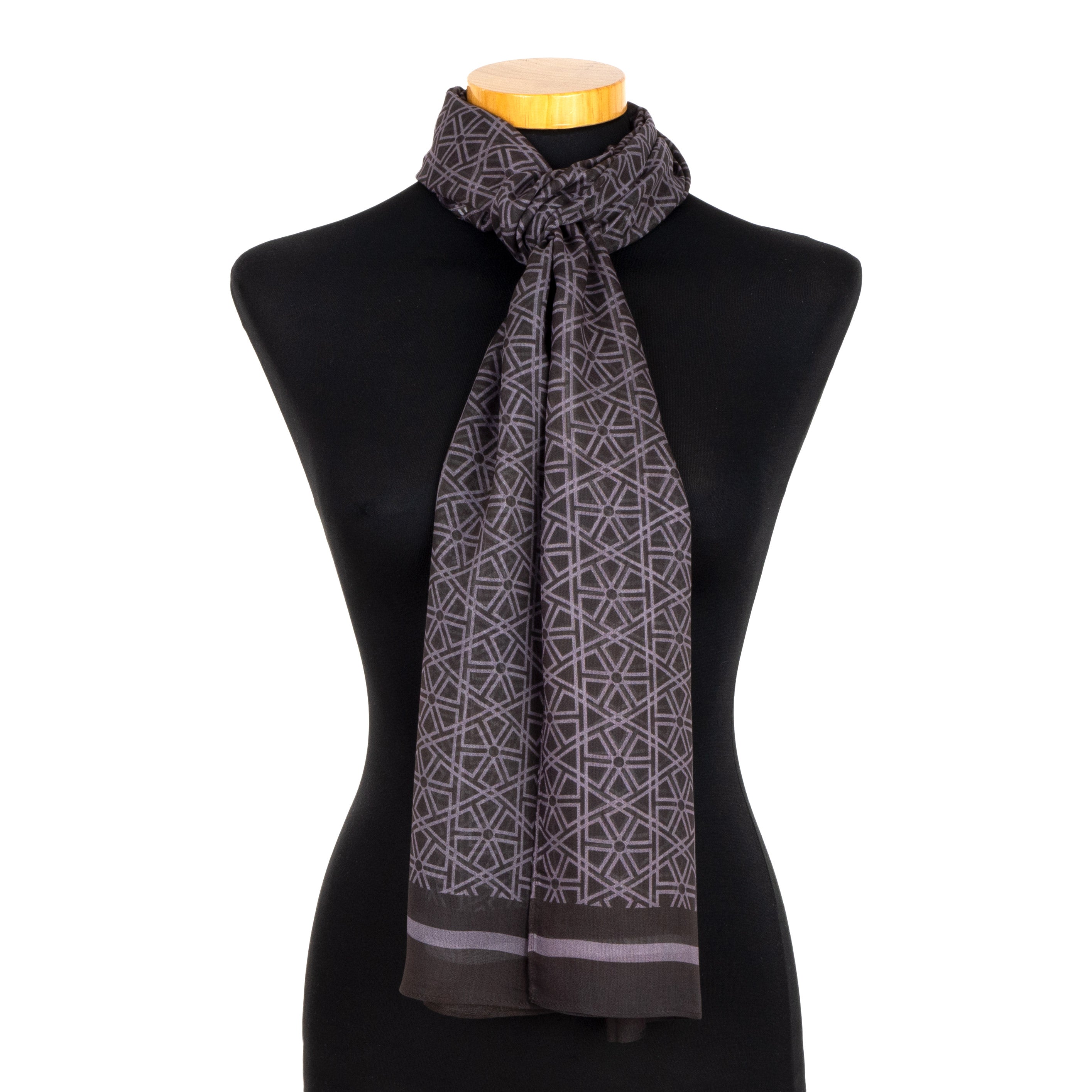 A black mannequin displays the Black and Gray Scarf Taif v1, featuring Alhambra-inspired geometric motifs and a solid border, elegantly tied around the neck.