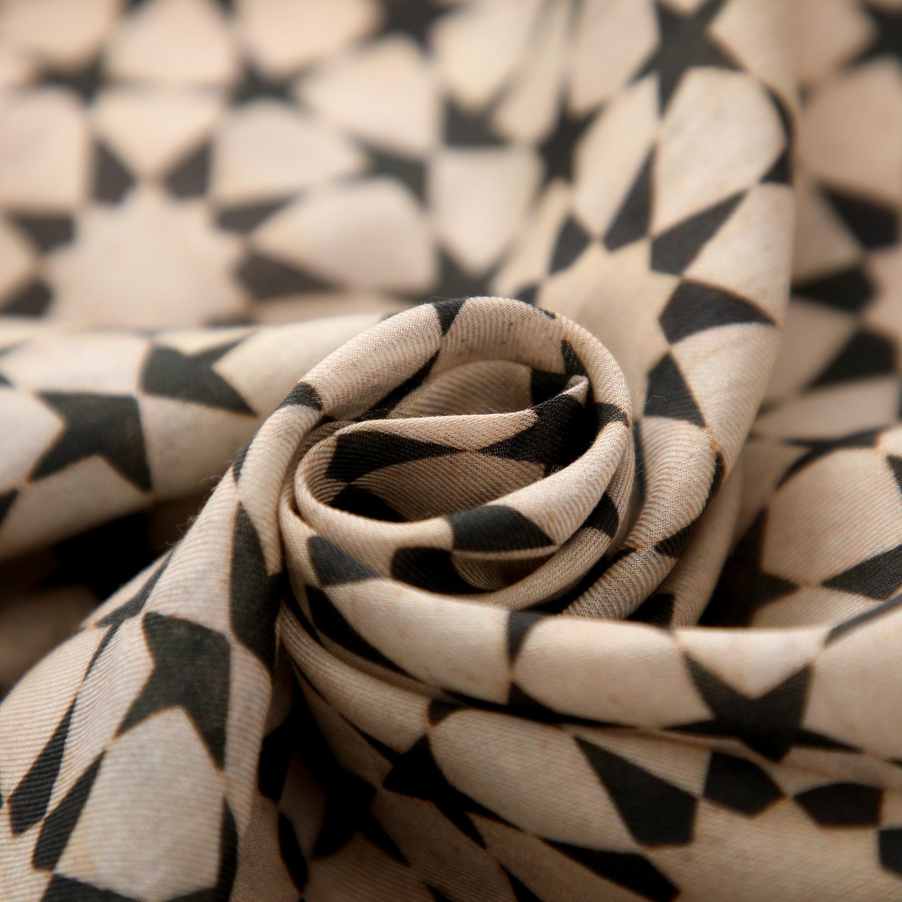 A close-up of the Beige and Black Scarf - Sahara, featuring a geometric star pattern inspired by Andalusí Islamic art