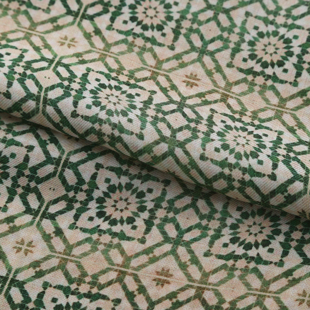 Folded fabric detail of the Green Modal Scarf Alhambra Lattice Azahar, showing the green lattice and the mustard and terracotta border