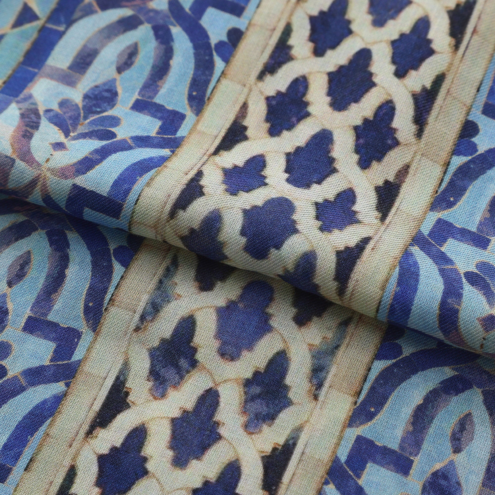Folded fabric detail of the Blue Modal Scarf Andalusian Tiles Almunia, showing the cobalt star field and the arcade border