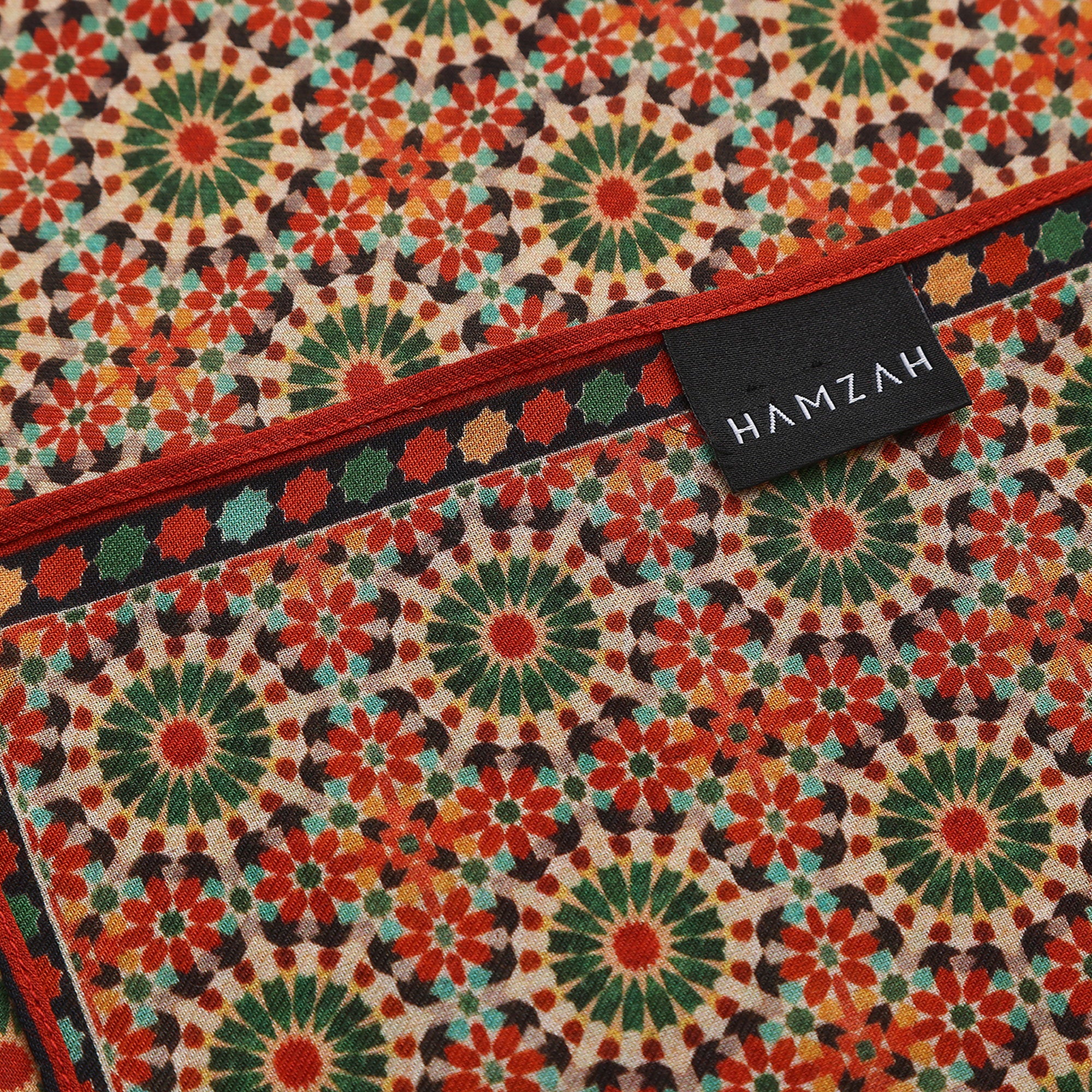 Folded corner of the Red and Green Modal Scarf Mosaic Rosettes Zubaida, showing the border and the hem