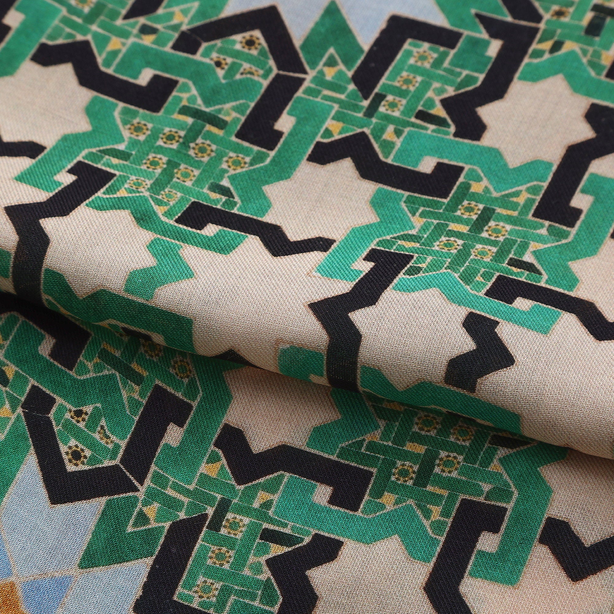 Folded fabric detail of the Green Modal Scarf Alhambra Interlace Salma, showing the emerald interlace and pale blue stars