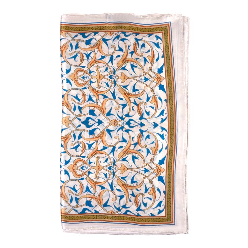 The Turkish Print Inspired Silk Scarf Rumi by Hamzah is crafted from satin silk with hand-rolled edges. It showcases intricate scrolling vines and leaves in orange, blue, and gold, framed by a narrow golden border.