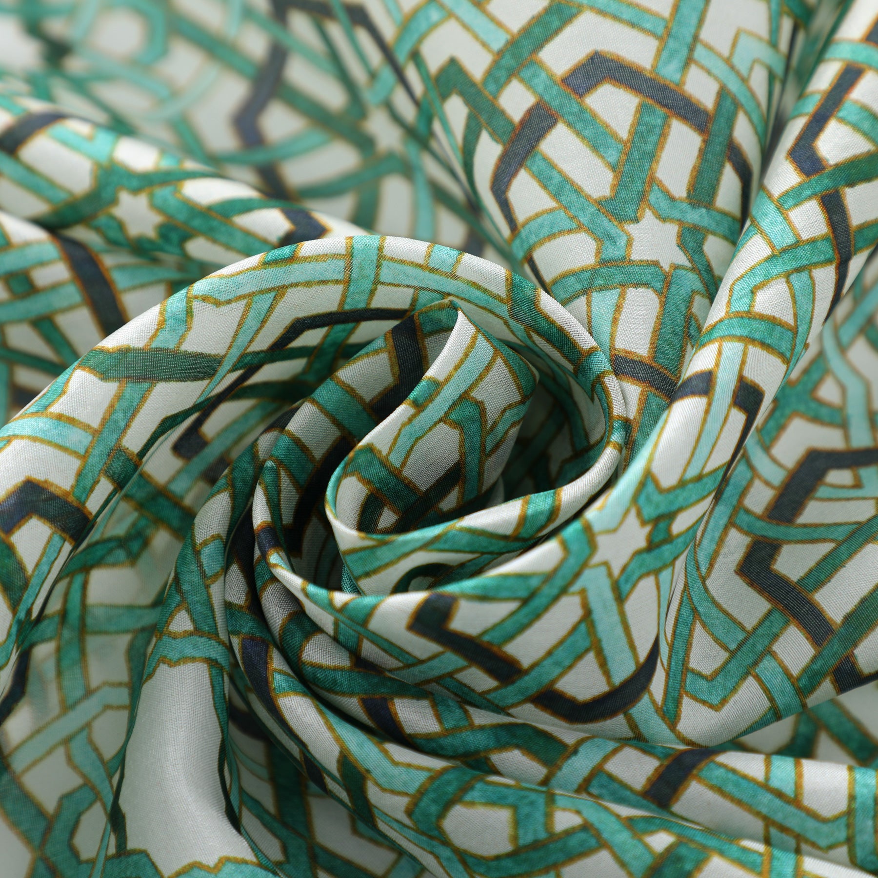 A close-up of the Green Islamic Art Tessellation Silk Scarf Hijaz V2, featuring a geometric green, gold, and black pattern inspired by Islamic Art, artfully gathered into soft folds and swirls.