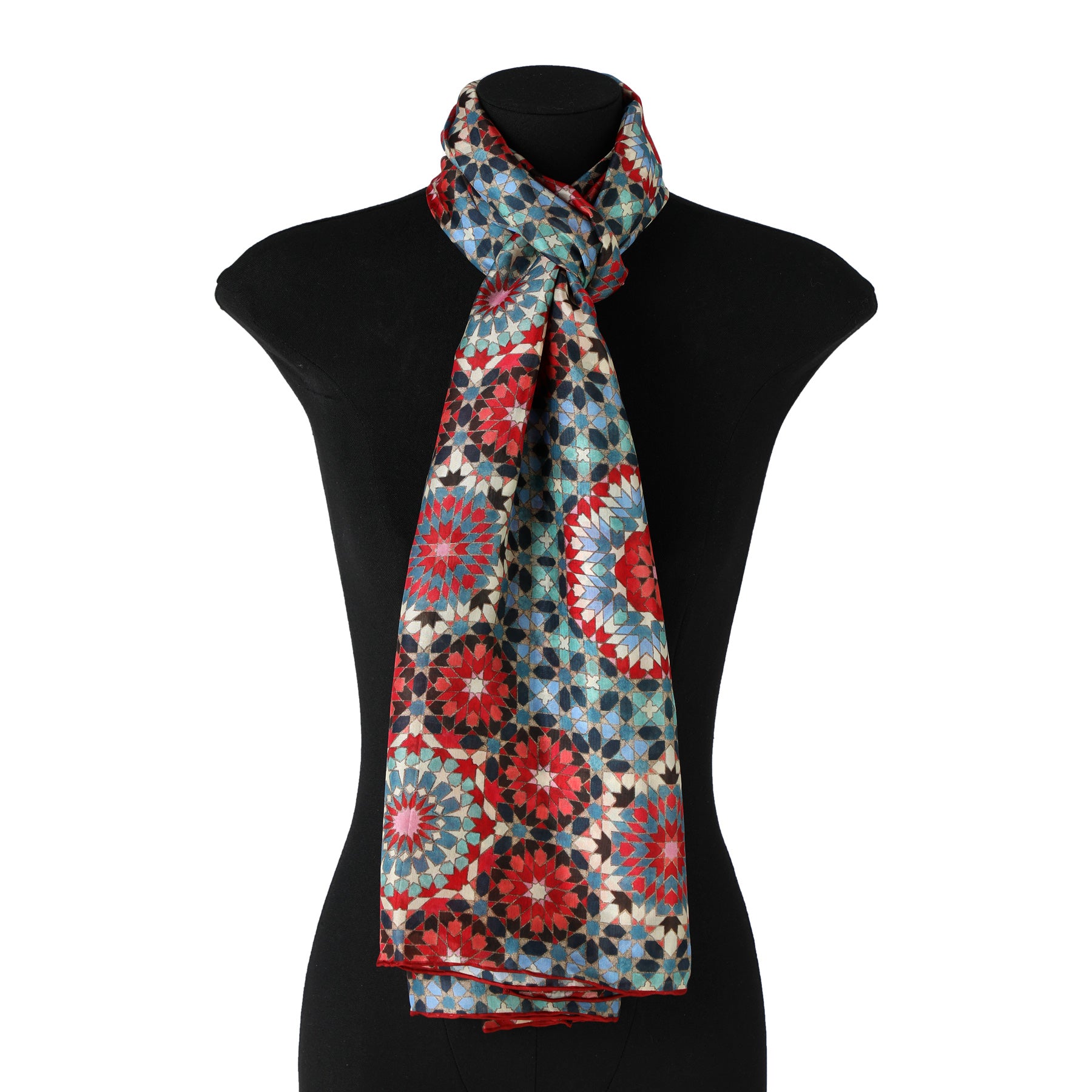 The Multicolor Silk Scarf Baraka V1, featuring a geometric mandala-inspired pattern in red, blue, teal, and cream reminiscent of Islamic Art, is draped around the neck of a black mannequin bust.