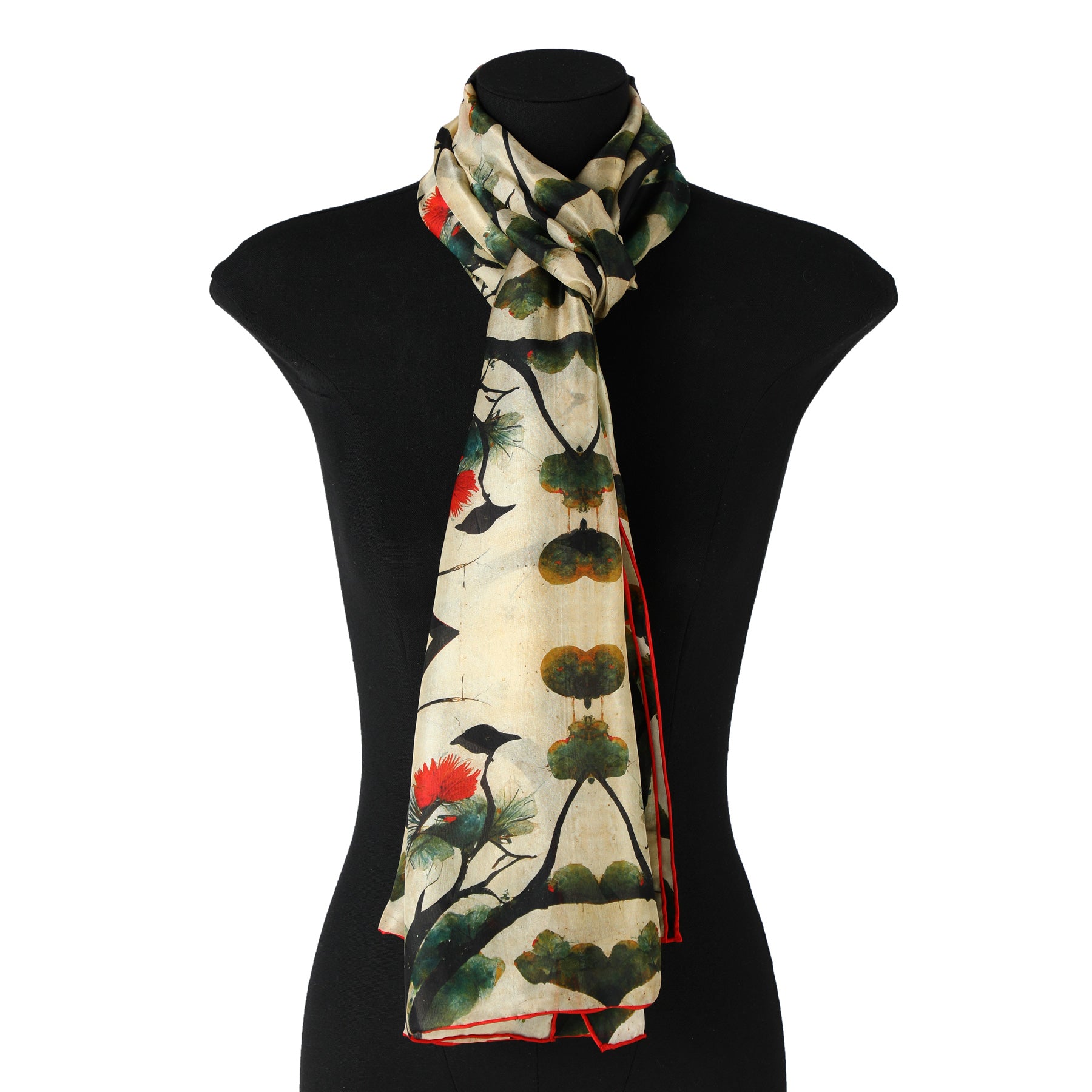 The Japanese Art Scarf by Hamzah, crafted from 100% Habotai silk, showcases bird and red blossom designs akin to Japanese art on a black mannequin torso. Its intricate patterns and vibrant colors add an artistic flair to any display.