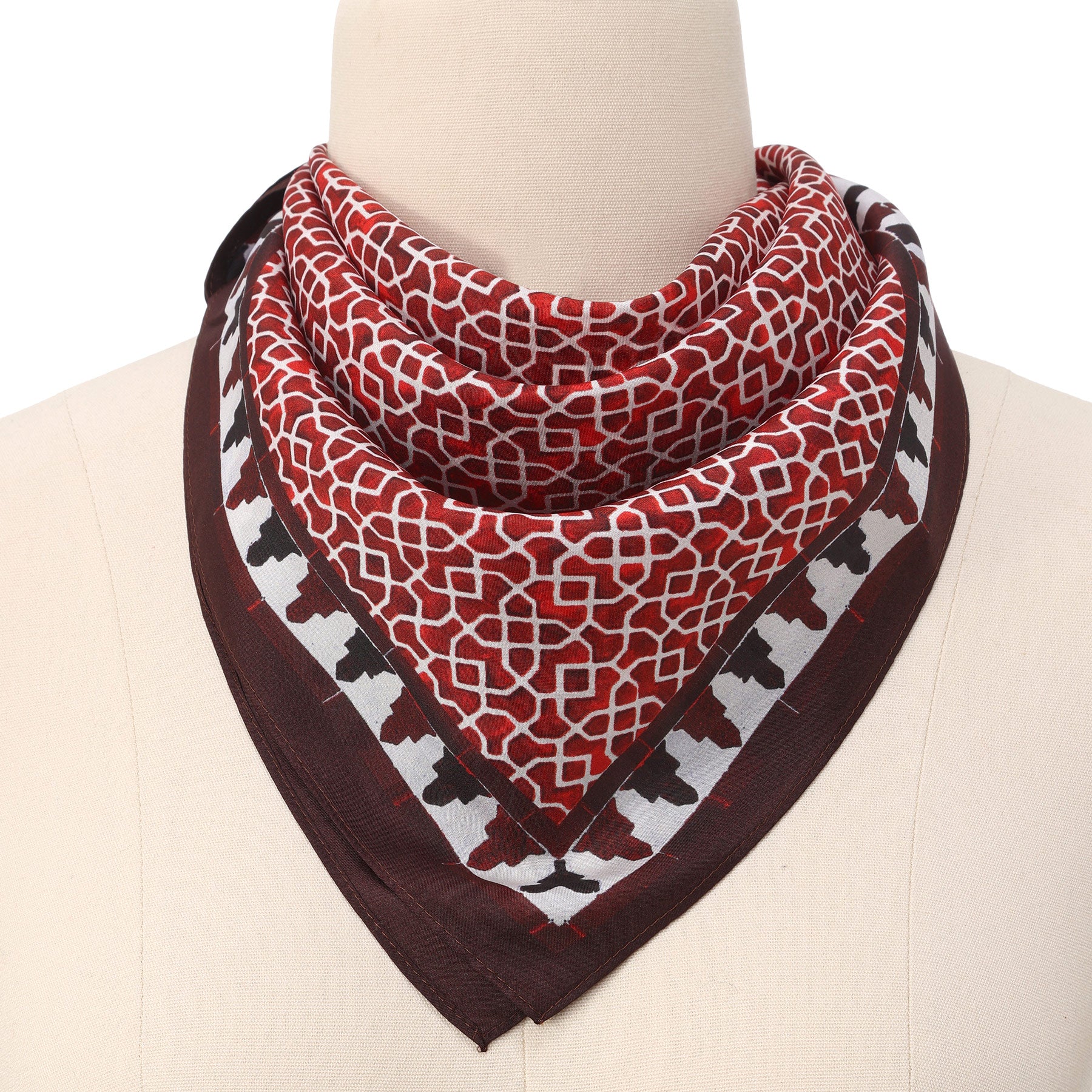 A mannequin displays the Red Square Scarf 100% Silk, featuring an Islamic art-inspired red and white geometric center with a dark brown and white border, neatly folded and draped around the neck.