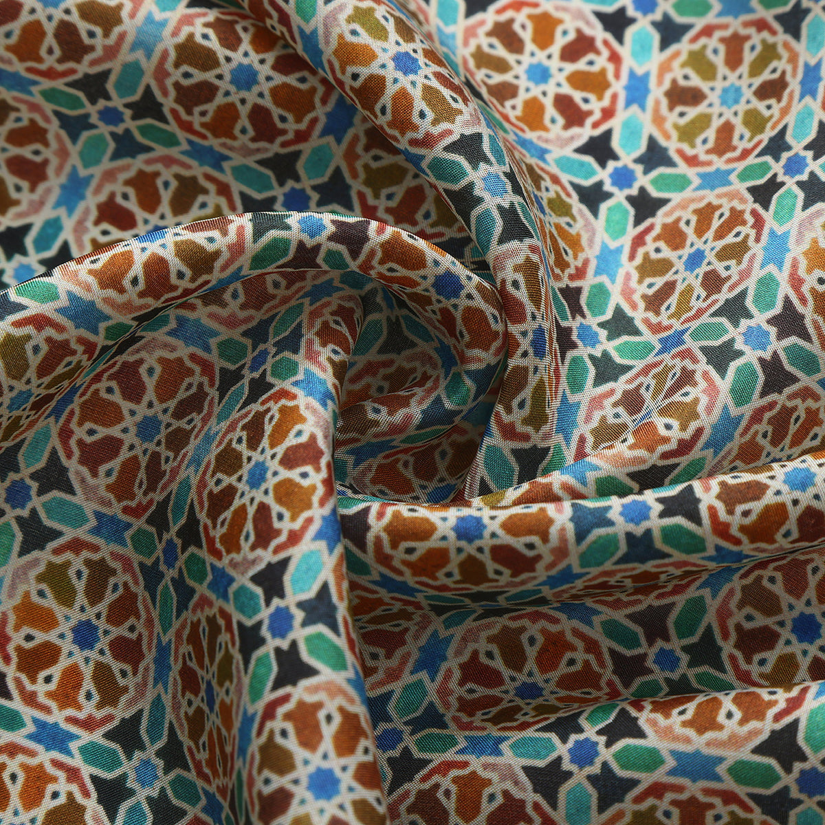 Close-up of the Wallada silk print: the orange wheels and turquoise fill on navy