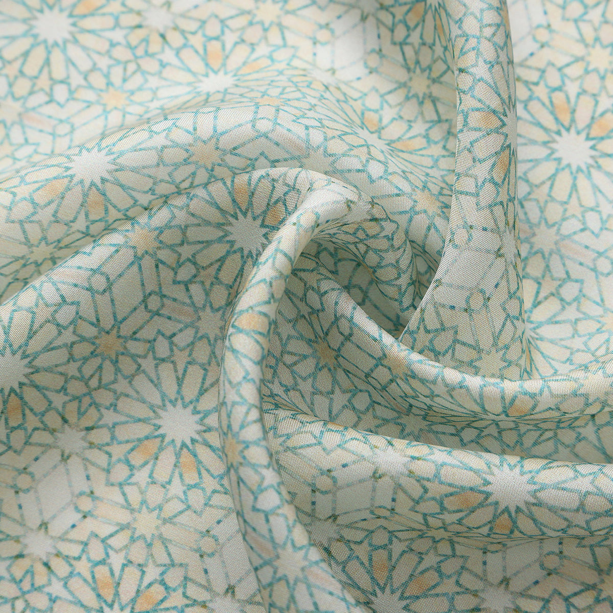 Close-up of the Lubna silk print: the fine turquoise star lattice on ivory
