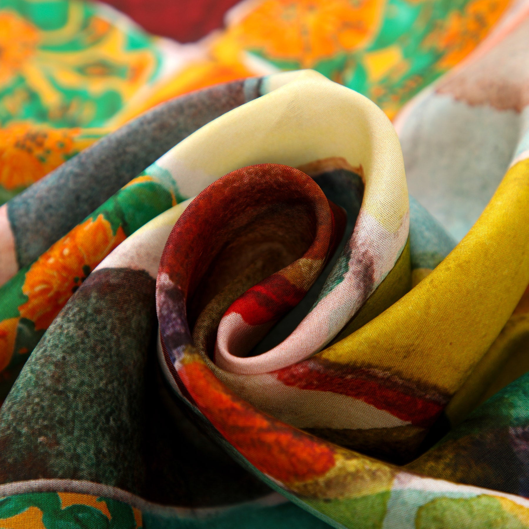 A close-up of colorful, semi-transparent fabric with swirling folds, showcasing the vibrant Gaudí inspired Silk Scarf La Mirada—a Mediterranean wearable art piece in shades of yellow, red, green, and orange.