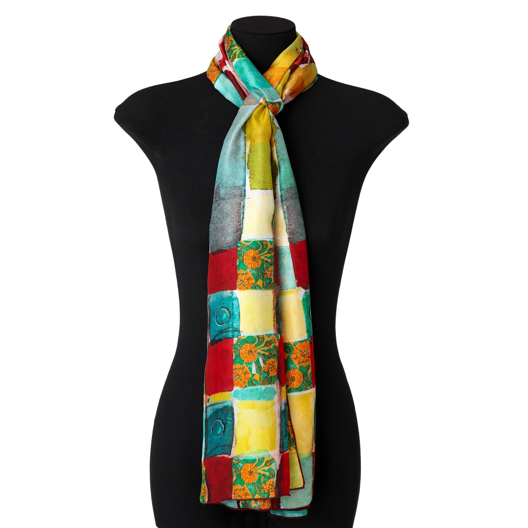 A mannequin displays the Gaudí inspired Silk Scarf La Mirada—colorful with red, yellow, green, blue, and patterned squares—draped neatly around its neck.