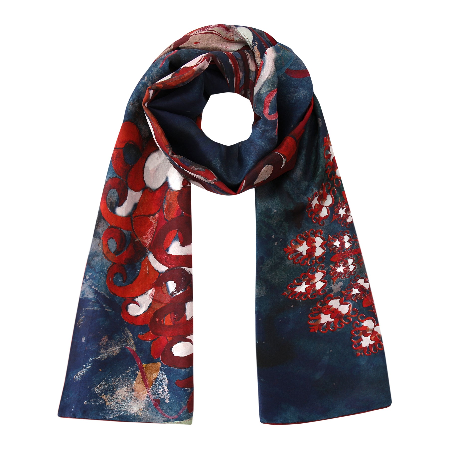 The Navy Blue Silk Scarf Plumas al Viento features a dark silk background adorned with abstract red, white, and pink floral and swirl patterns, elegantly looped with both ends hanging down.
