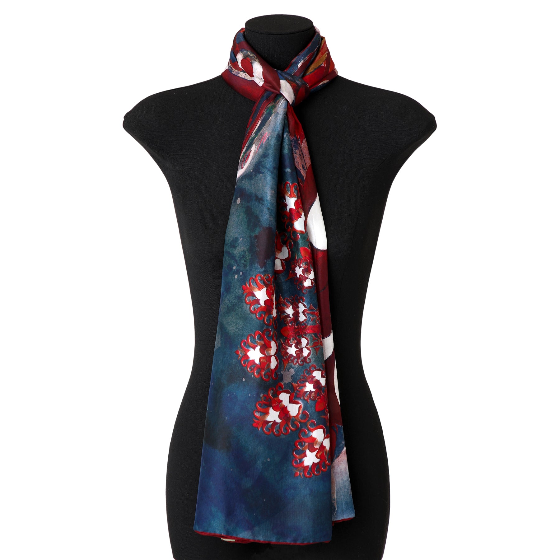 A mannequin displays the Navy Blue Silk Scarf Plumas al Viento, featuring vibrant abstract patterns in red, white, and blue, elegantly draped around the neck and hanging down the front.