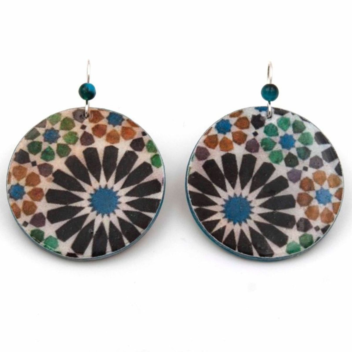 The Big Round Colorful Earrings Benameji by Azul Añil are round recycled paper earrings with geometric patterns and floral designs in blue, black, green, and brown hues. They feature a central blue starburst design and a top small blue bead, reflecting Islamic-inspired art in handmade jewelry.