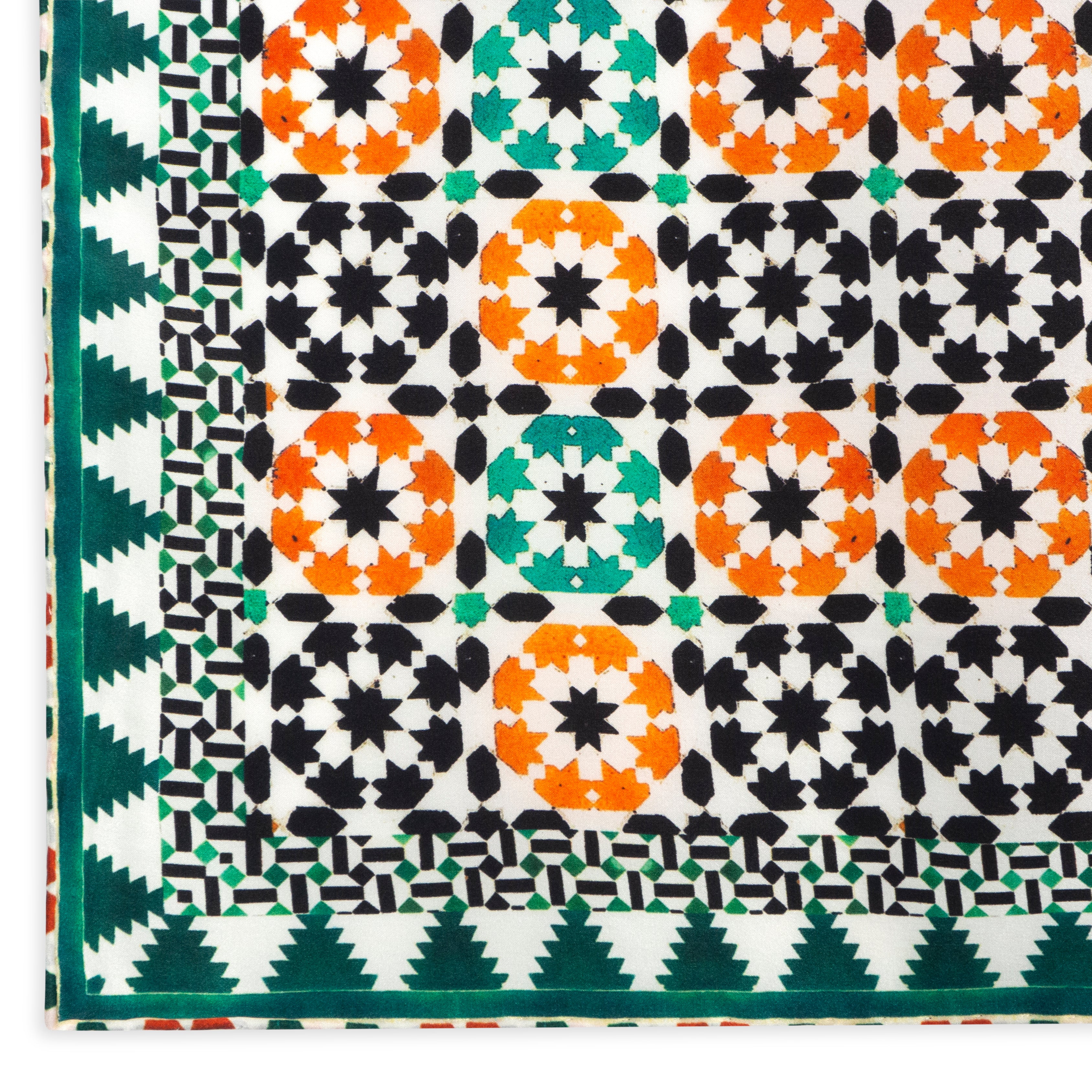 The Islamic Art Square Silk Scarf Sabika Green features a geometric pattern of orange and green star shapes with black accents, bordered by intricate designs, all on luxurious silk with elegant hand-rolled edges.