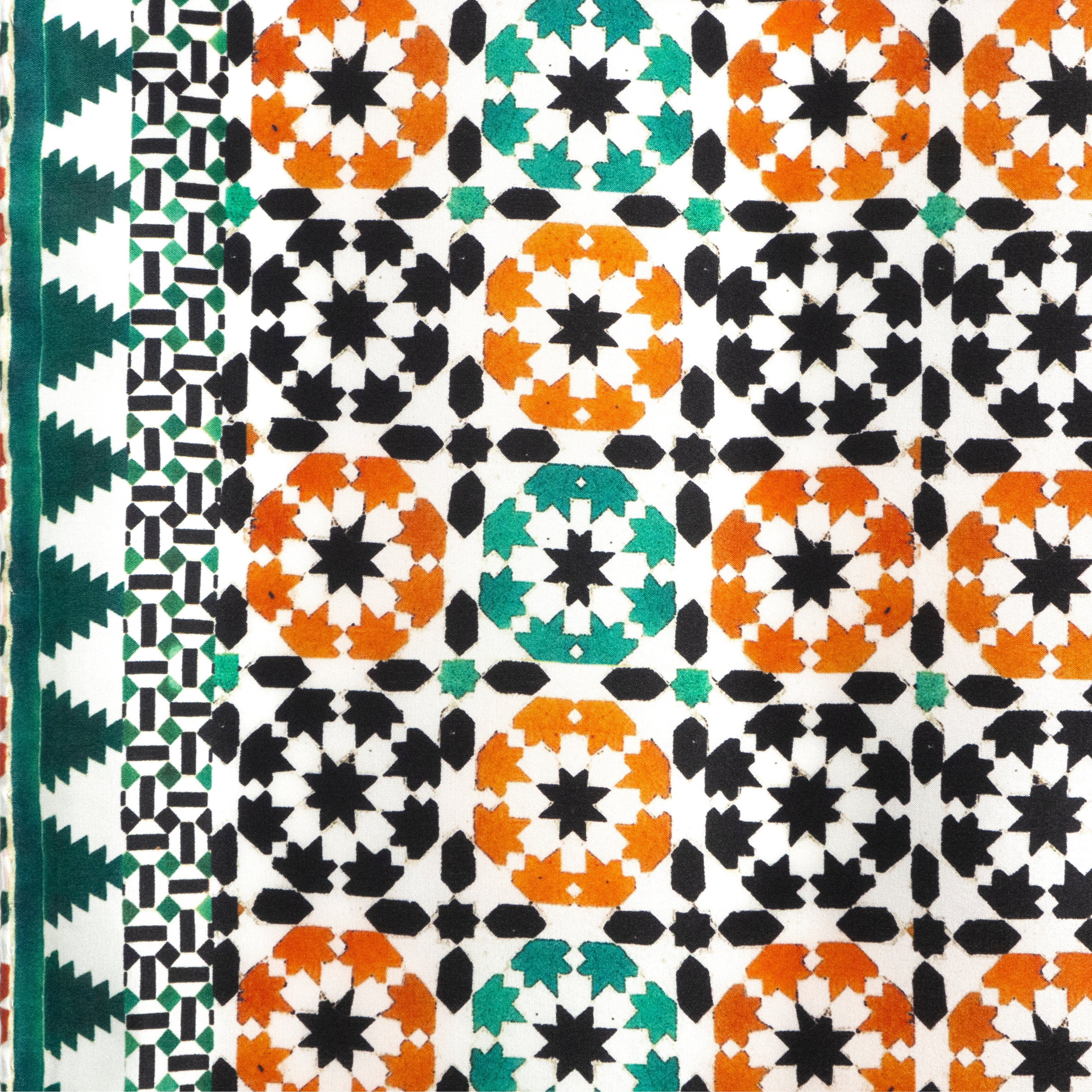 The Islamic Art Square Silk Scarf Sabika Green features alternating orange, green, and black star shapes within squares, a contrasting stripe of green and black geometric patterns on the left edge, and elegant hand-rolled edges.