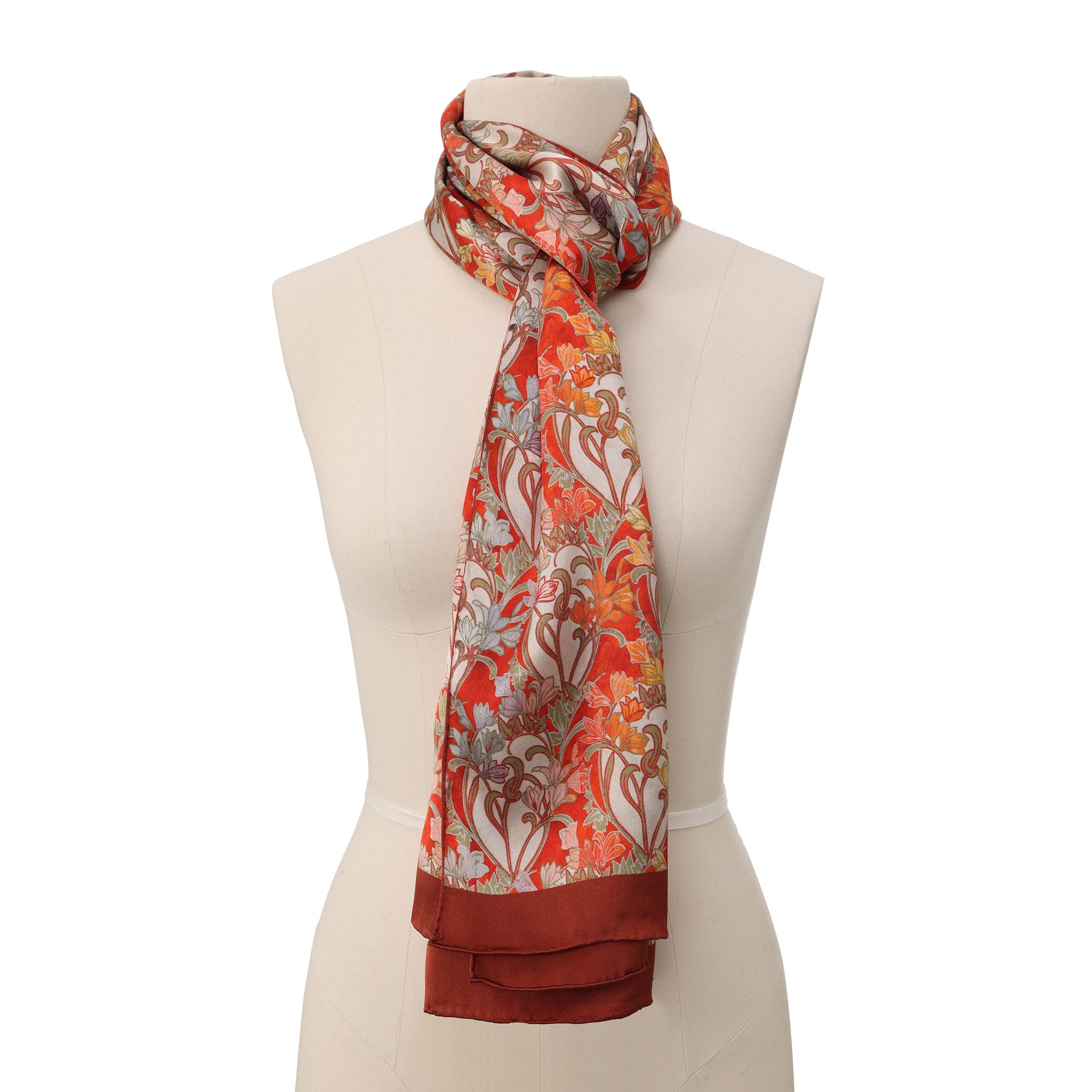 Swirled close-up showing the scarf’s intricate art deco-inspired florals in warm red, orange, and soft pastel hues.