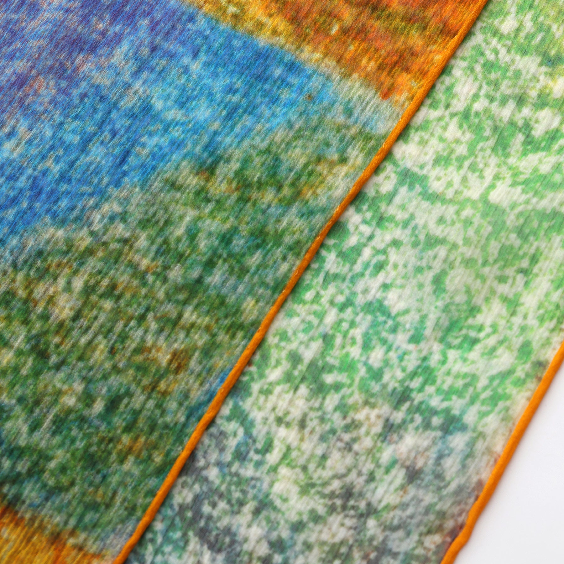 Close-up of the Multicolor Silk Scarf Calidoscopic, featuring two pieces of muslin silk with abstract, blurred blue, green