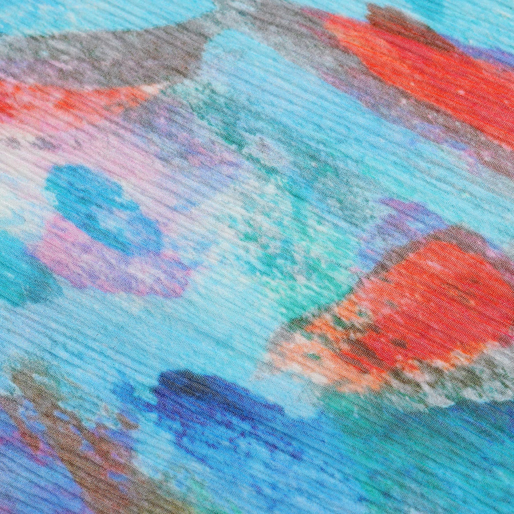 The Multicolor Silk Scarf Mar Rojo features vibrant blue, red, and orange brushstrokes on silk, evoking movement and color—perfect for adding Mediterranean-inspired flair to any outfit.