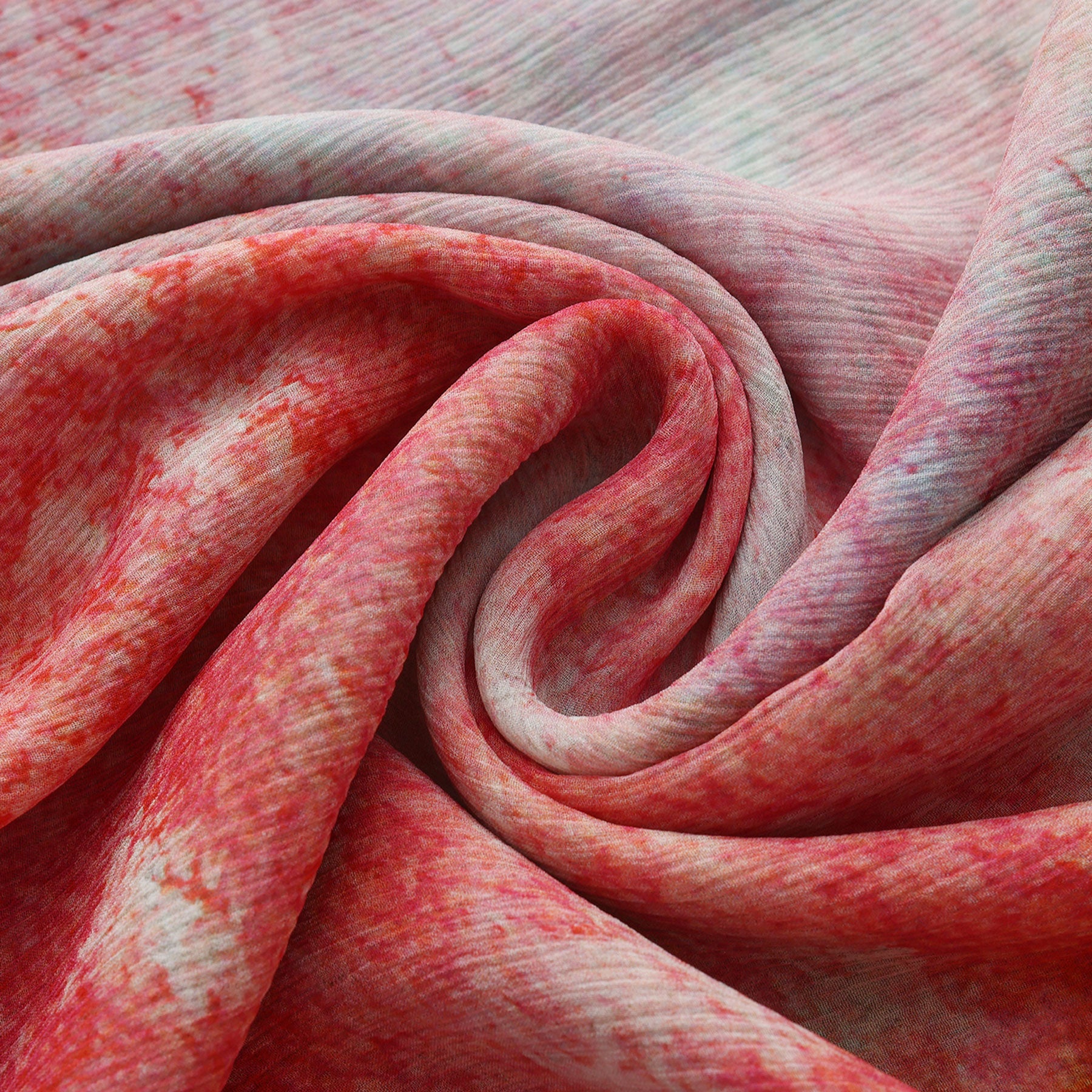 Close-up of the Multicolor Silk Scarf Fucsia Paradis, featuring red, pink, and white hues in swirling folds.