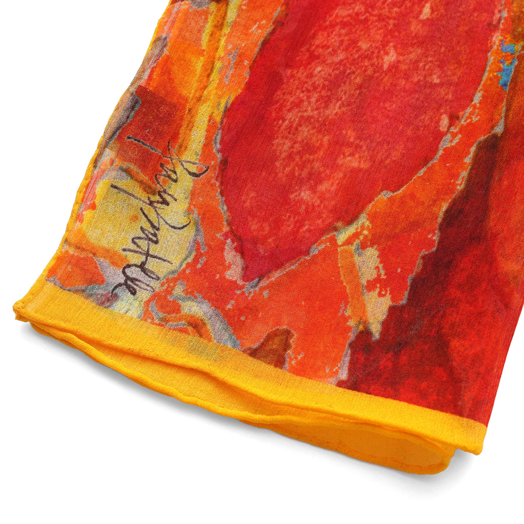 Close-up of the Multicolor Silk Scarf Demeter, featuring vibrant abstract patterns in red, orange, and yellow with a yellow hem and signature text on the edge—a true piece of wearable art.